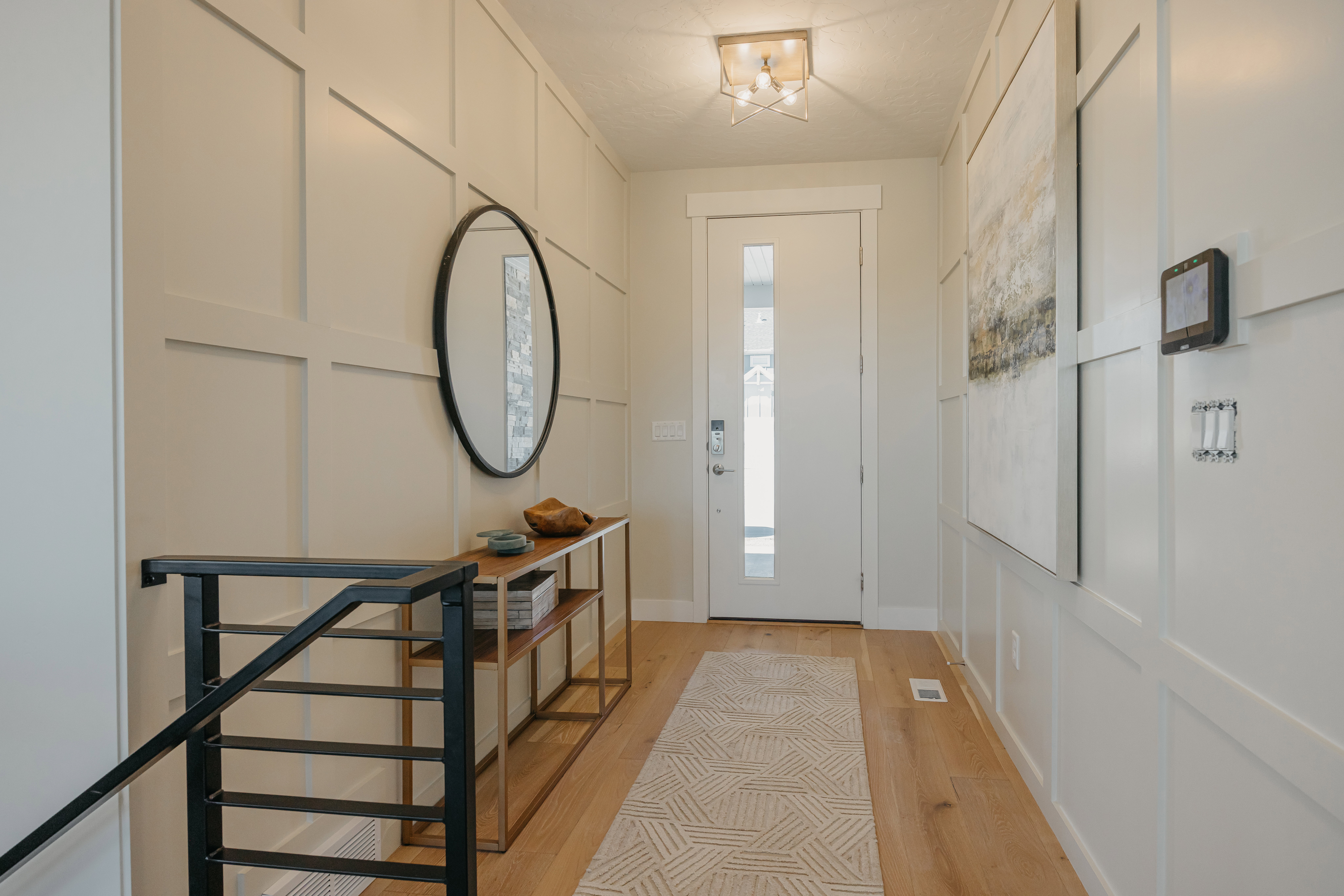 Entryway featuring board and batten wall paneling, a modern light fixture, and wood-finish flooring