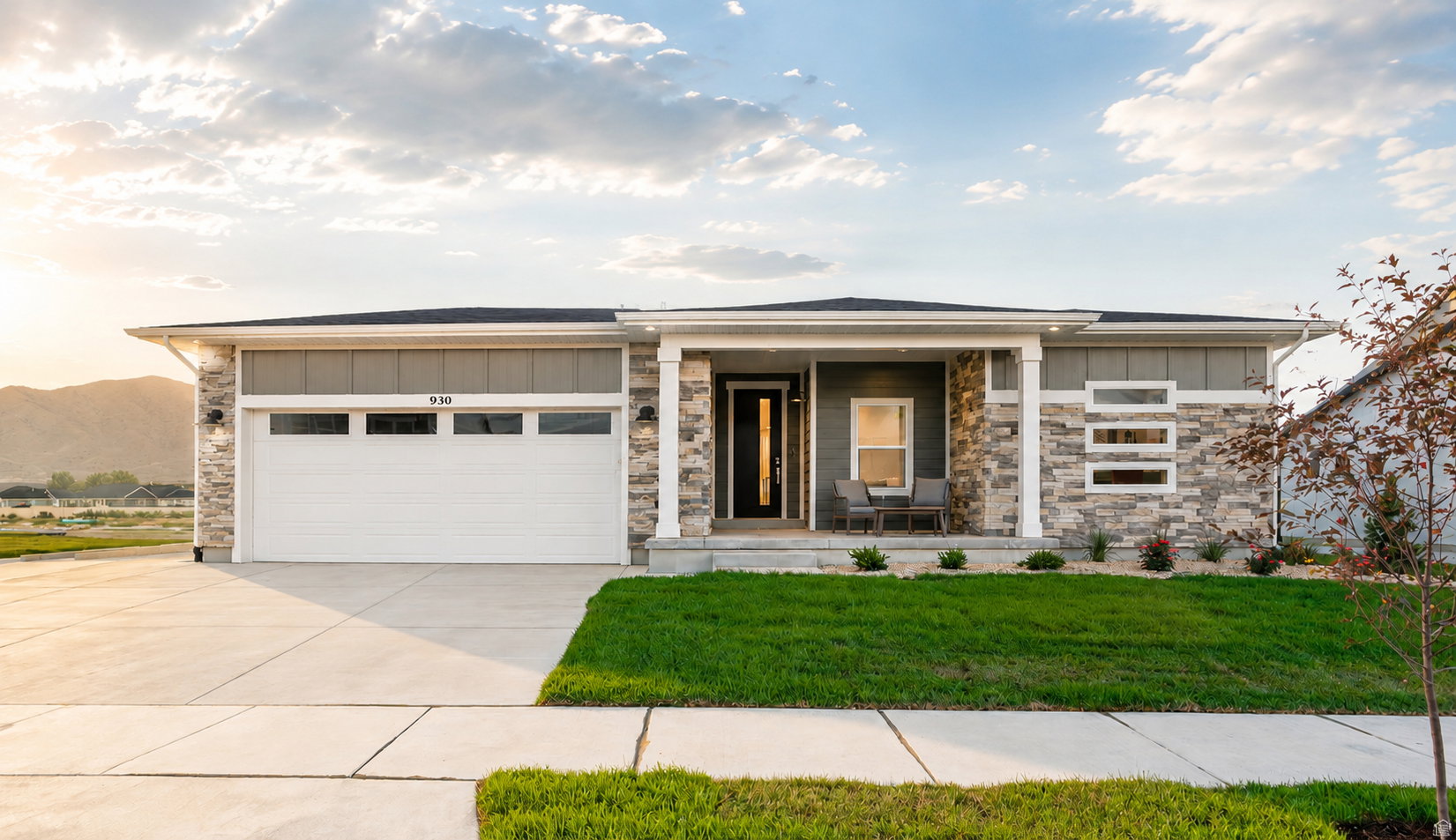 Ranch-style residence featuring a stone and siding facade, covered entry porch, white garage door with windows, and a landscaped front yard with a concrete driveway and sidewalk