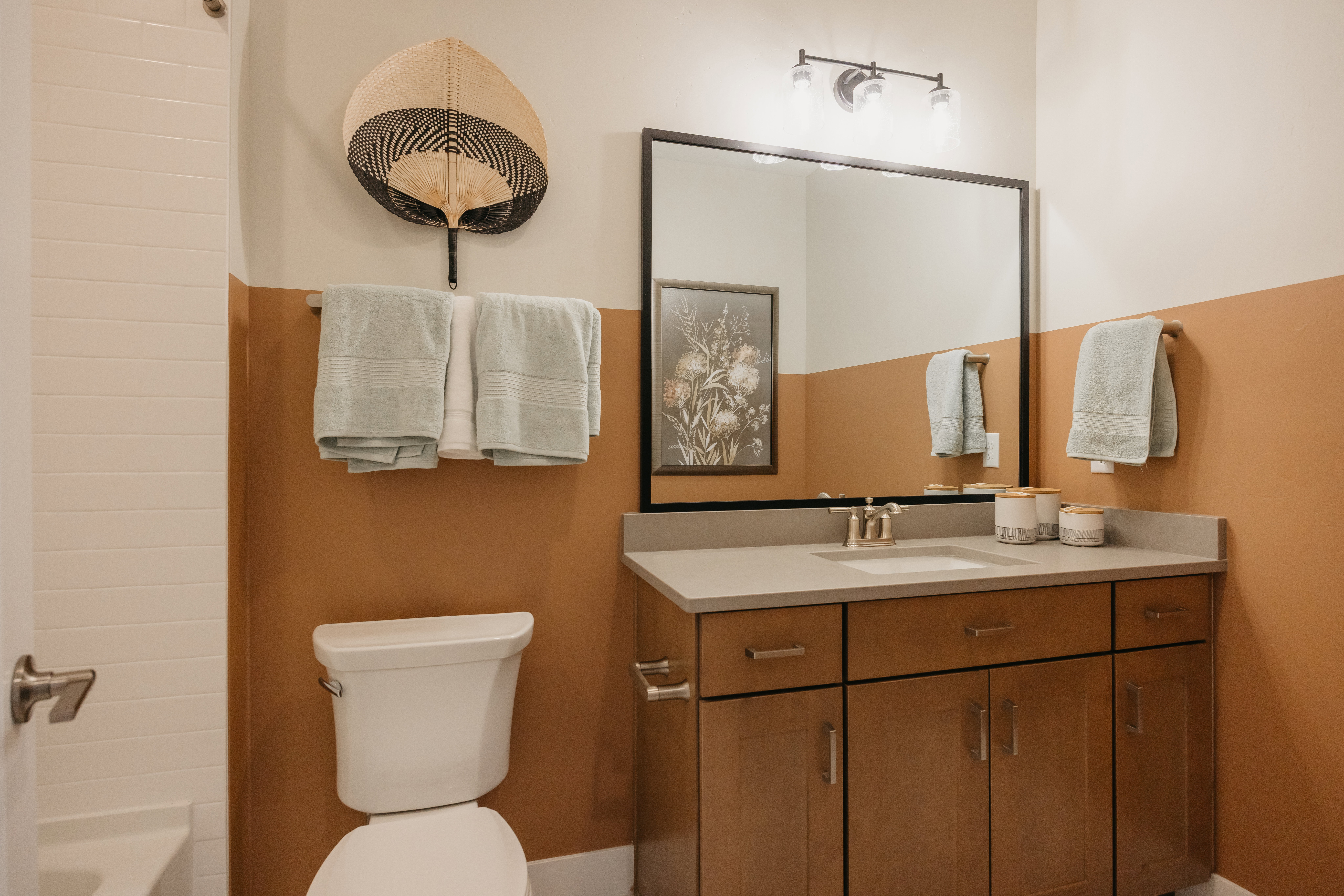 Bathroom featuring a wood-finish vanity with a light-toned countertop, an undermount sink, and a framed mirror
