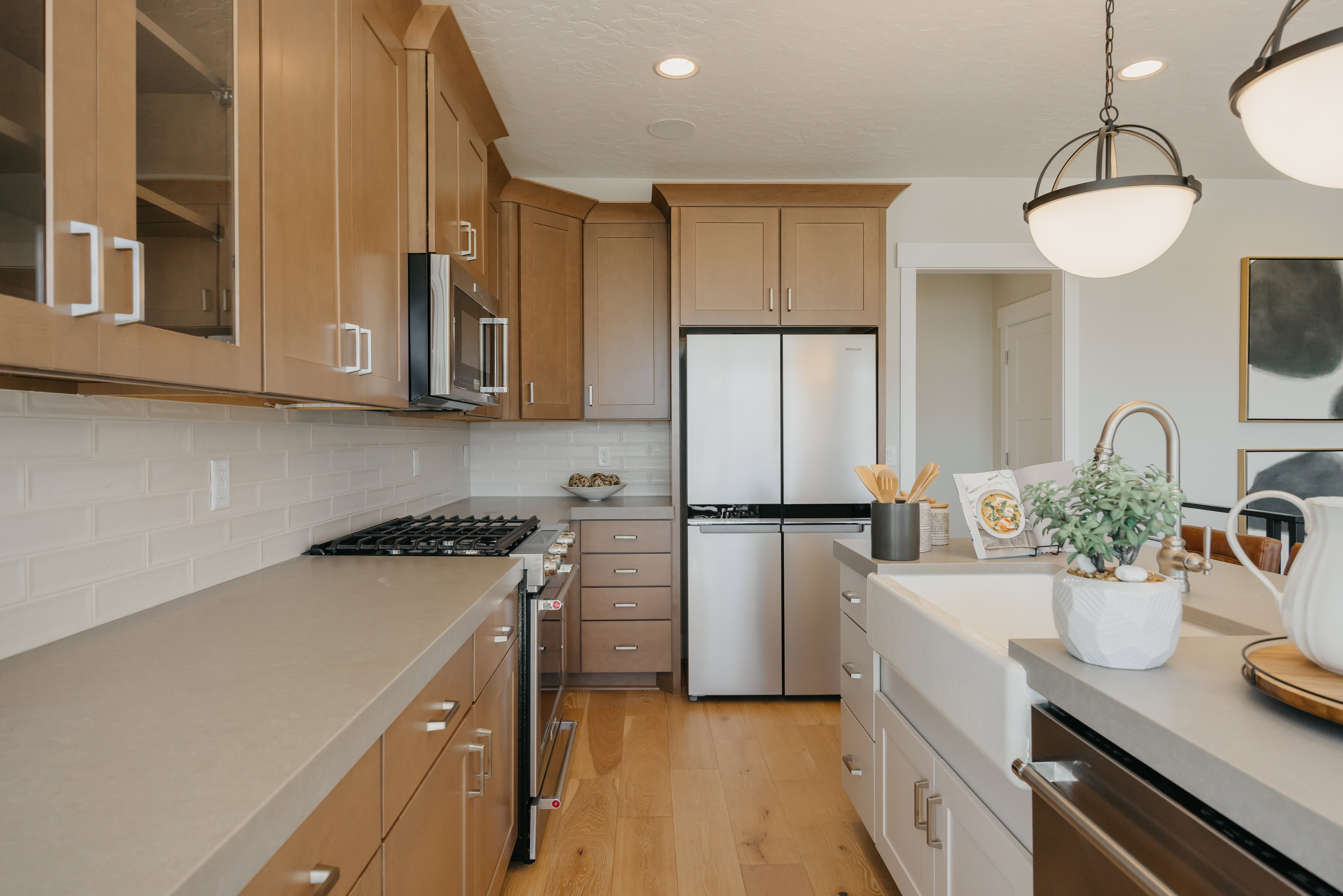 Kitchen featuring light wood cabinetry with glass-front accents, stainless steel appliances, and a gas range