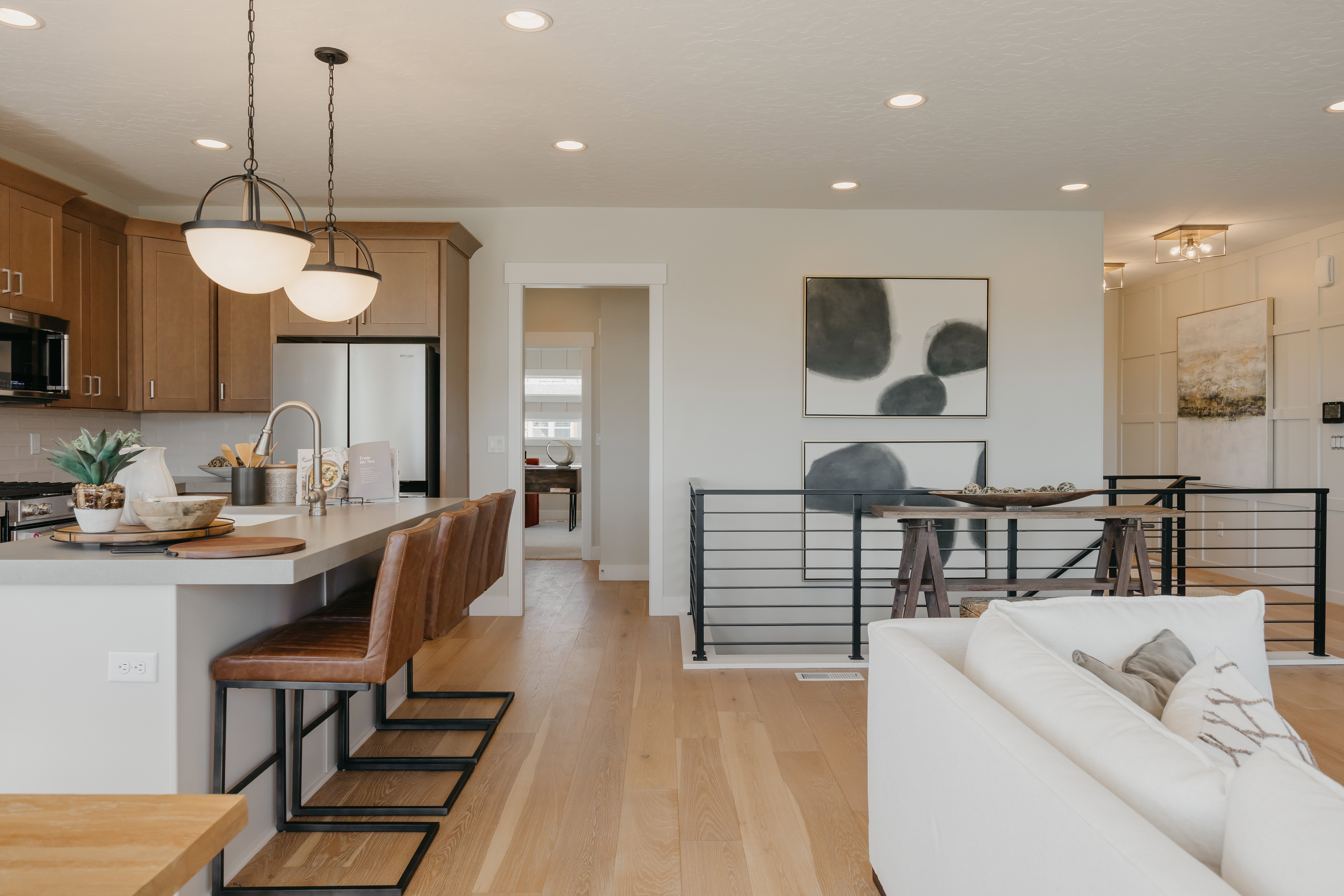 Kitchen island with a light-toned countertop, pendant lighting, stainless steel appliances, wood-finish flooring, and recessed lighting