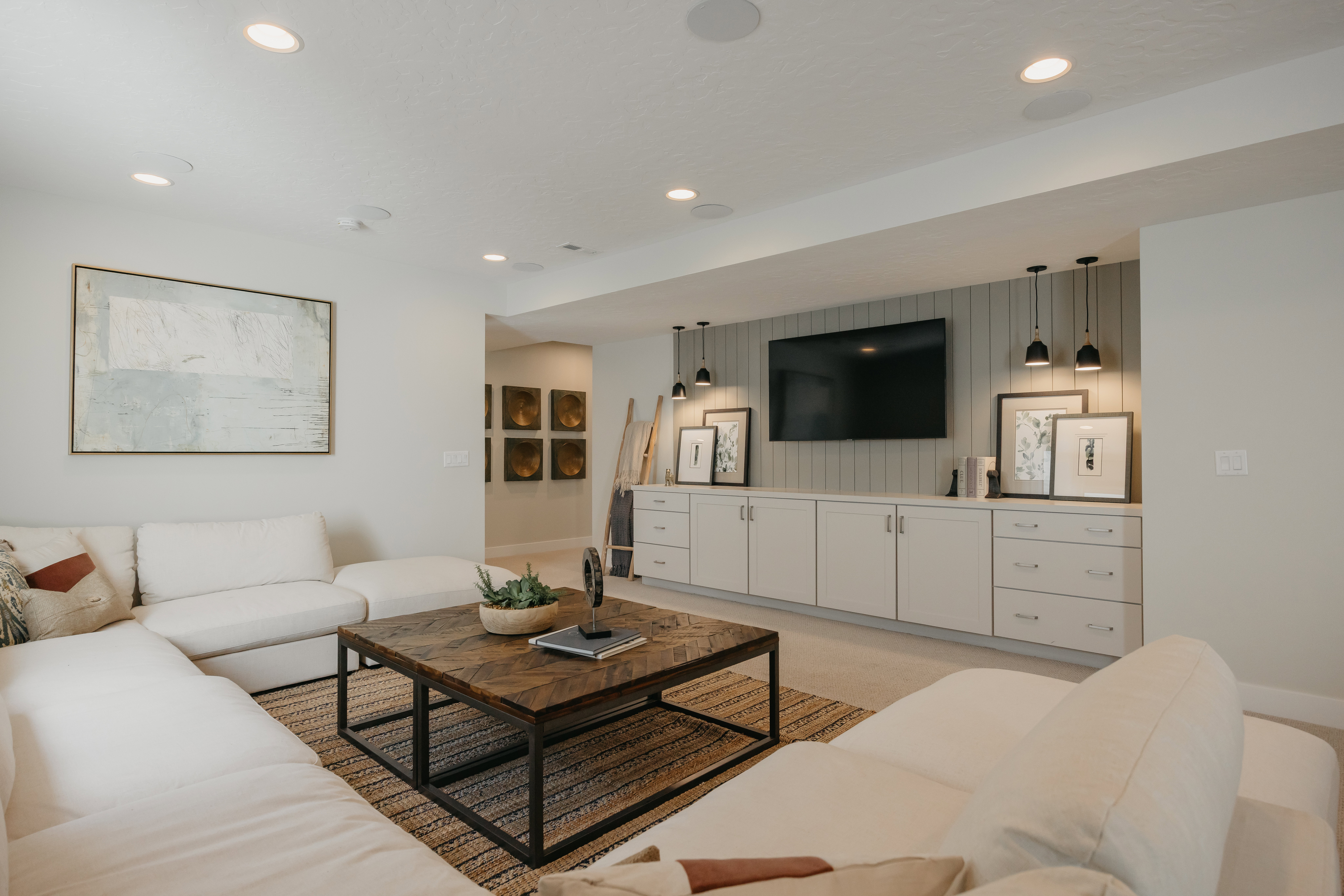 Entertainment area featuring a built-in media console with light-toned cabinetry and drawers, shiplap accent wall, and recessed ceiling lighting