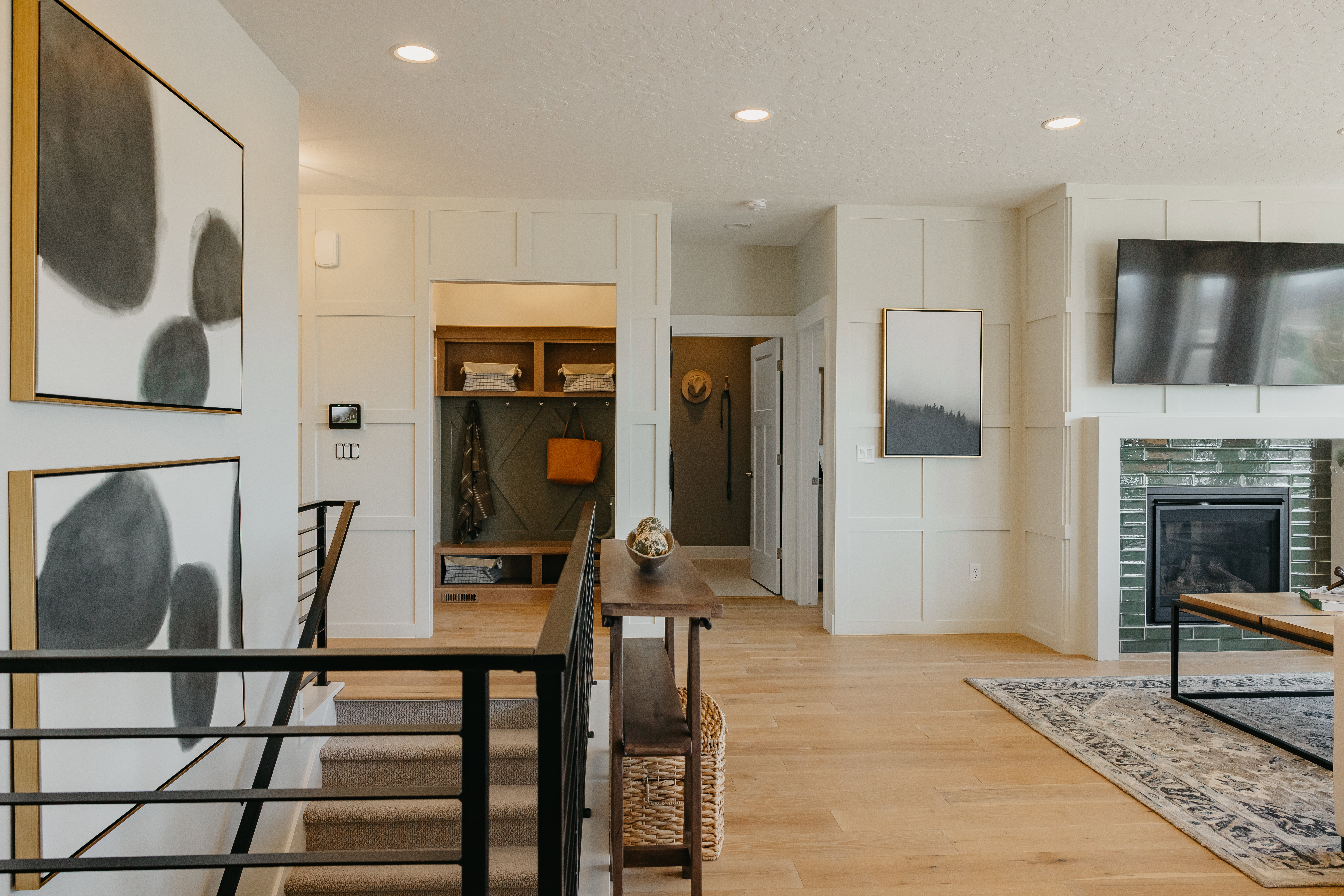 Recessed lighting illuminates wood-finish flooring and white board and batten wall accents