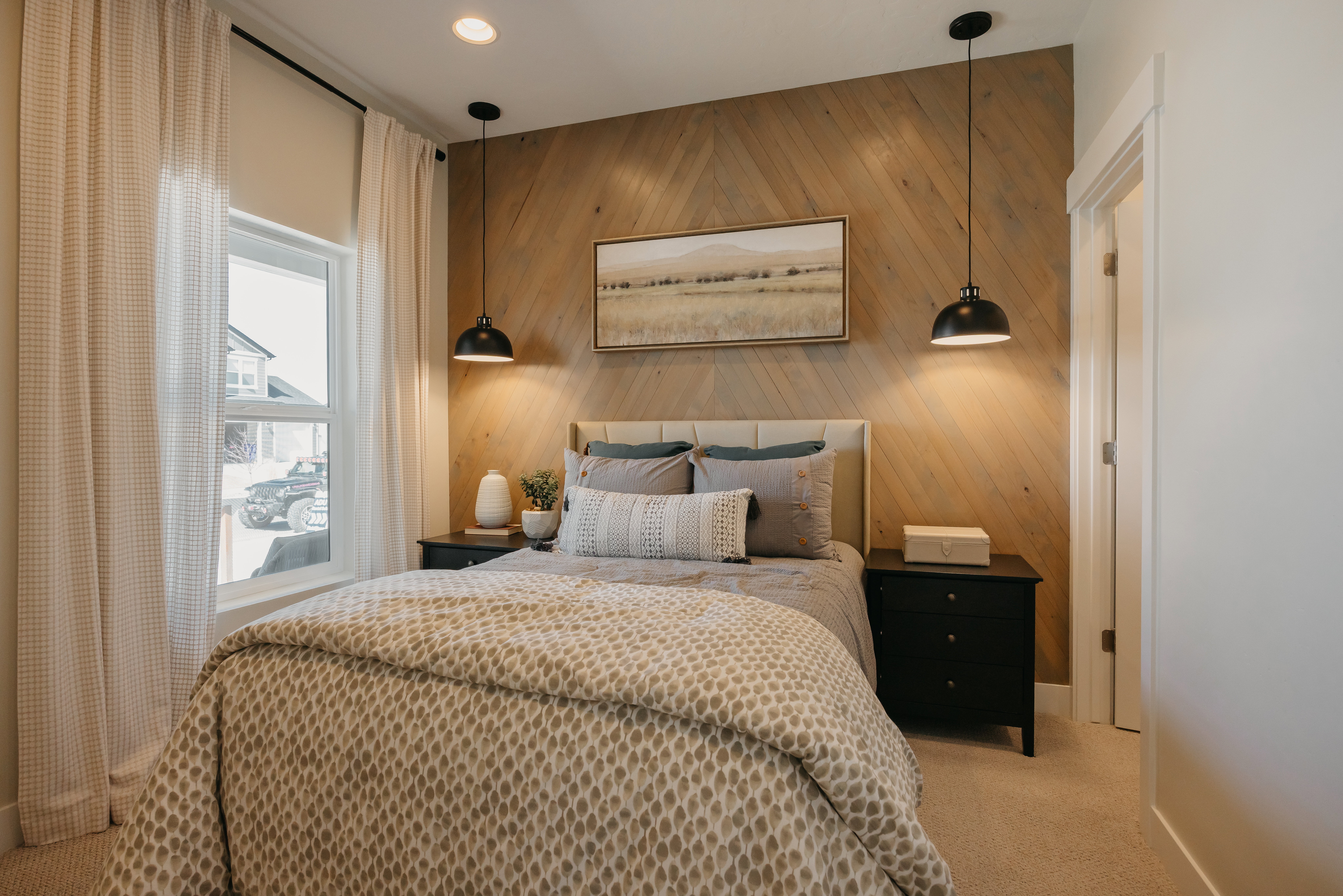Bedroom featuring a chevron wood-paneled accent wall, neutral carpeting, and a single window with curtain rods