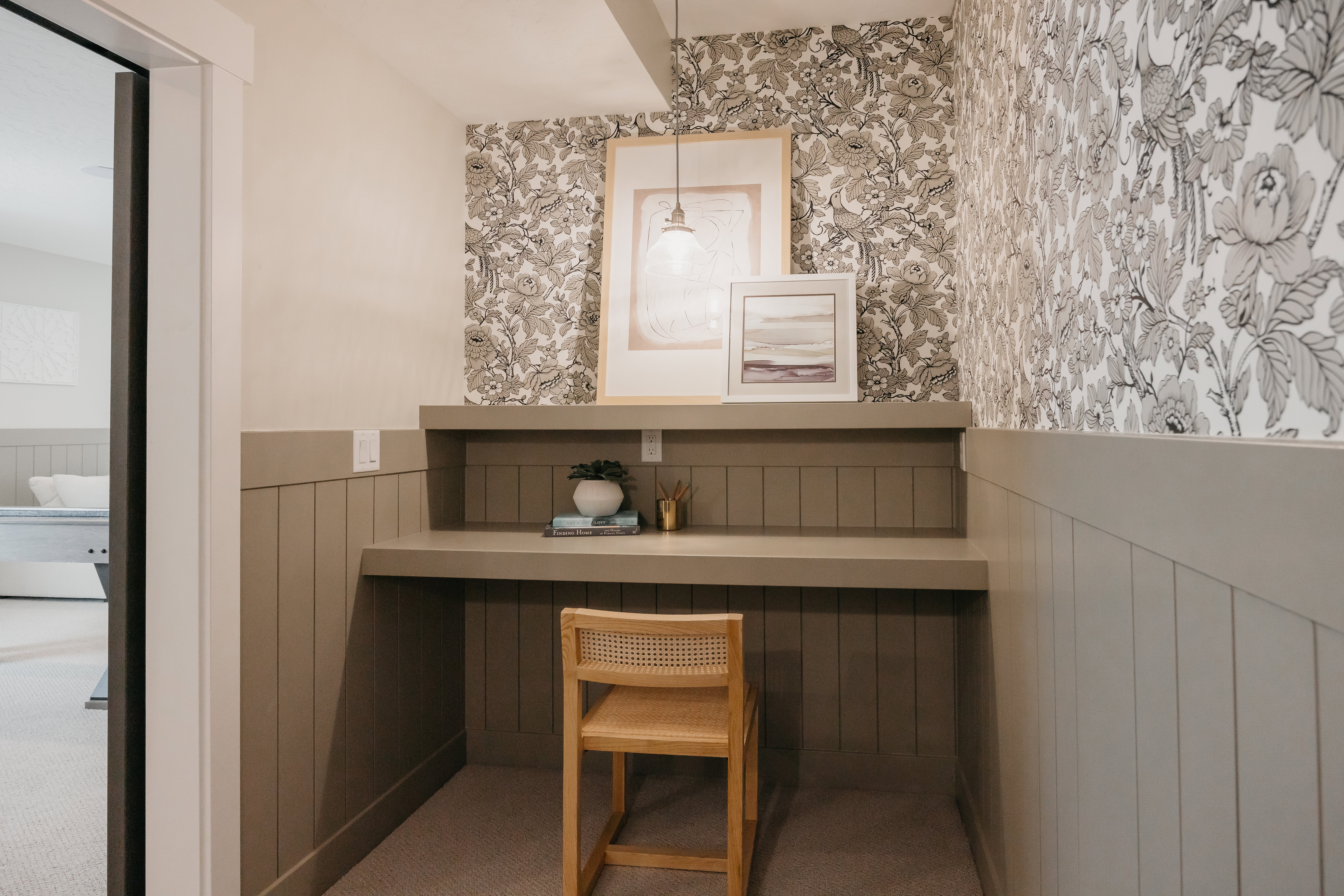 Dedicated built-in desk area featuring a neutral tone and floral wallpaper accent
