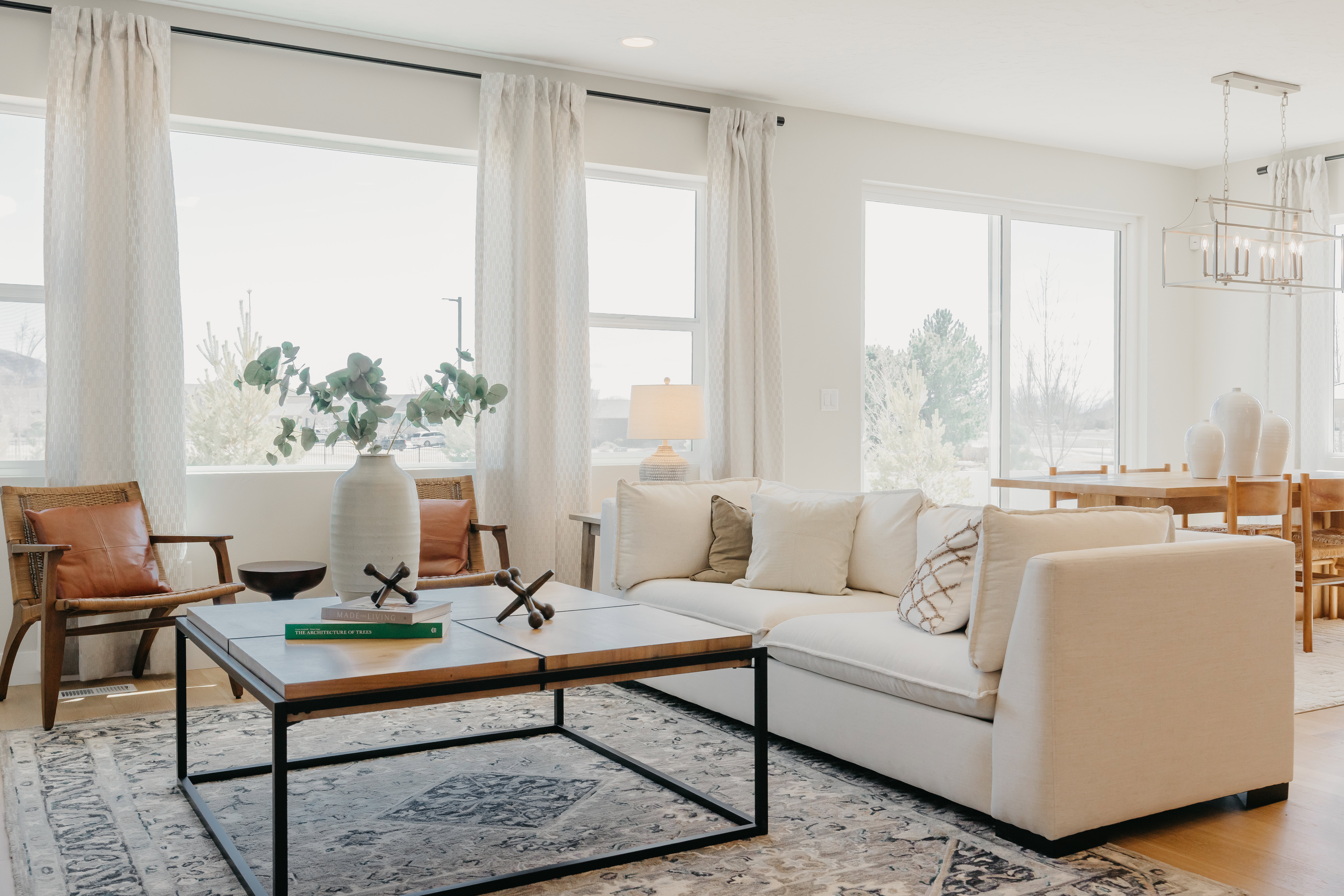 Spacious interior featuring expansive windows, light wood-finish flooring, a modern linear chandelier, and recessed lighting