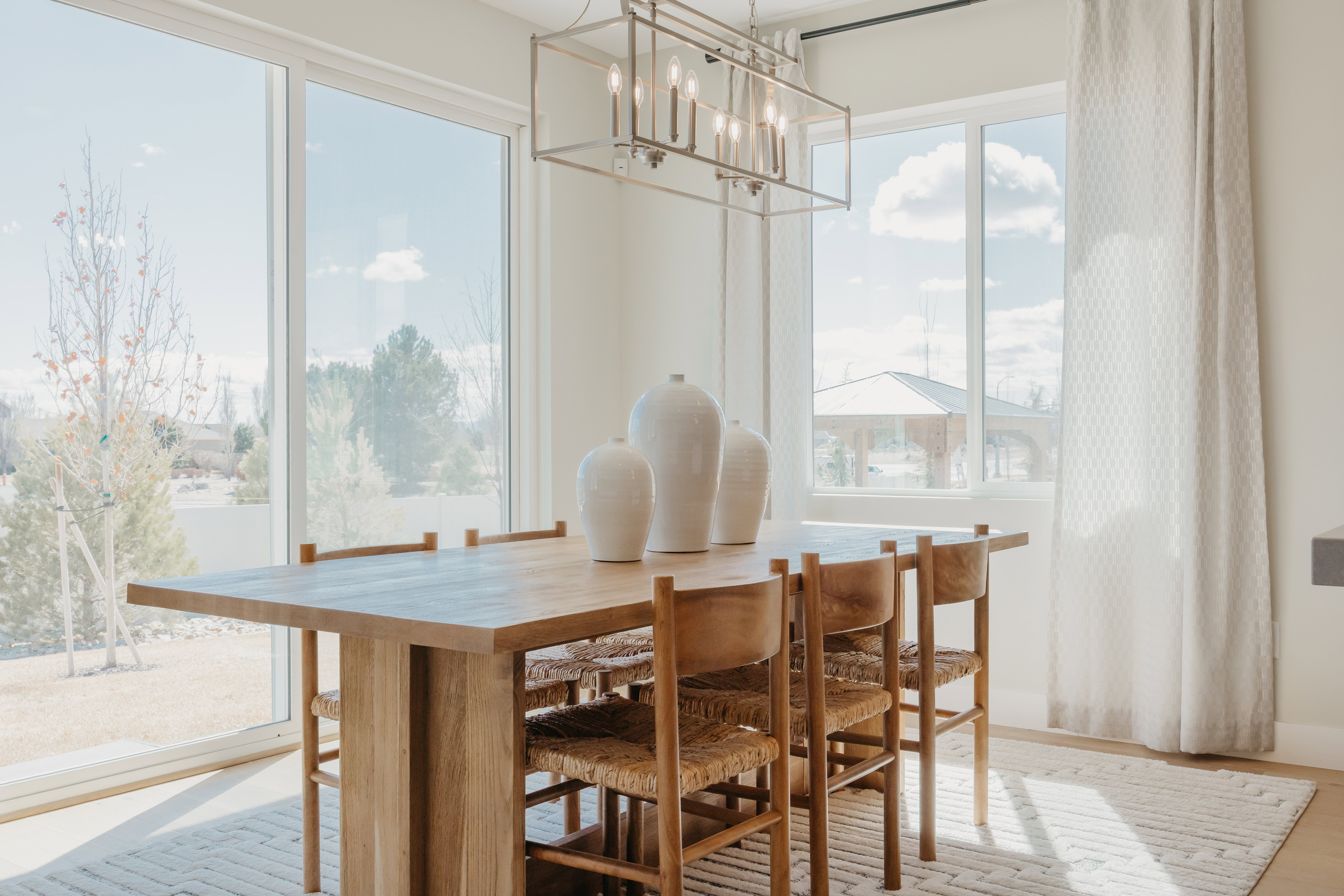 Dining space featuring a linear chandelier, expansive windows, light wood-finish flooring, and light-toned wall paint