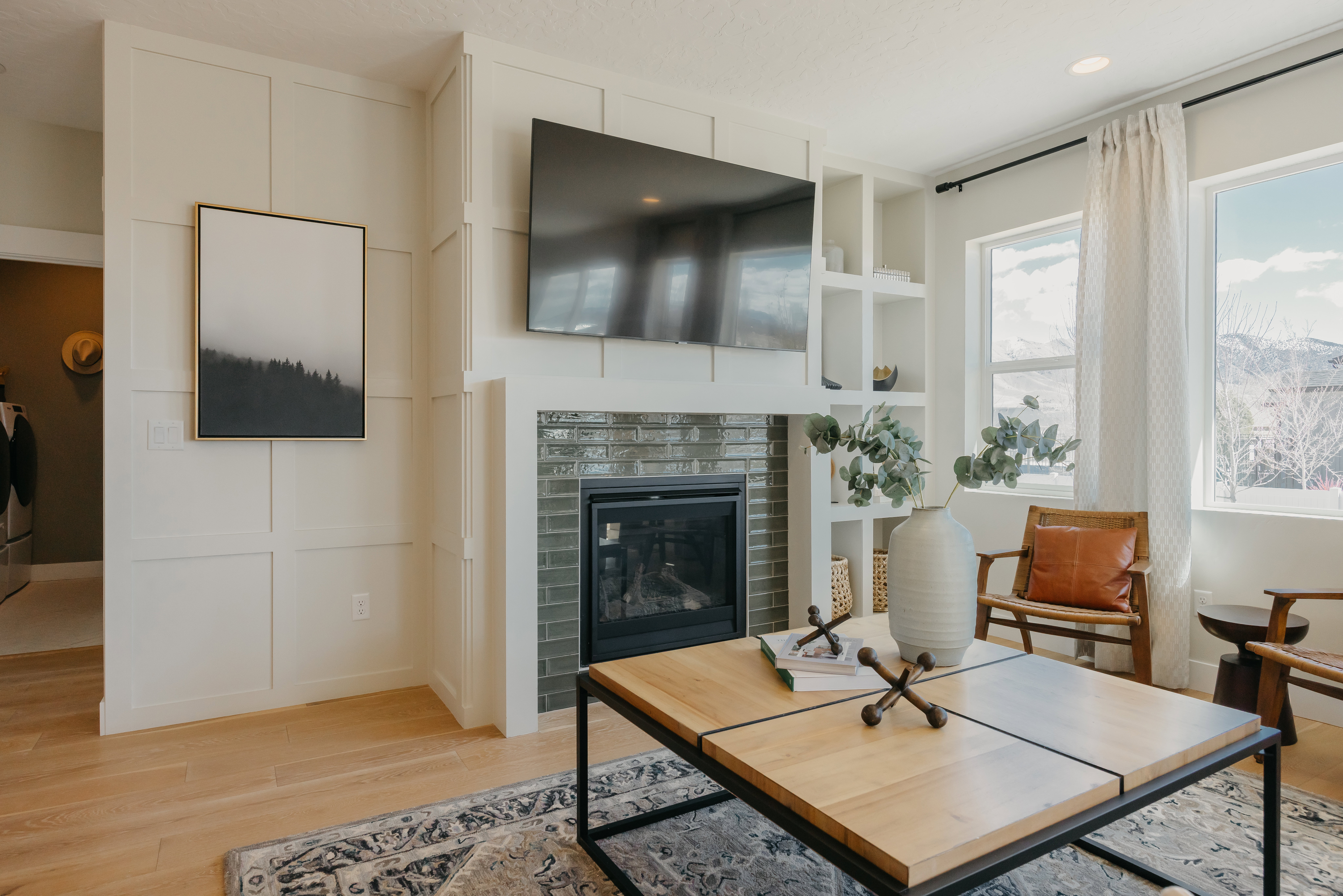 Living area featuring wood-finish flooring, white paneled walls, and a built-in fireplace with a dark tile surround