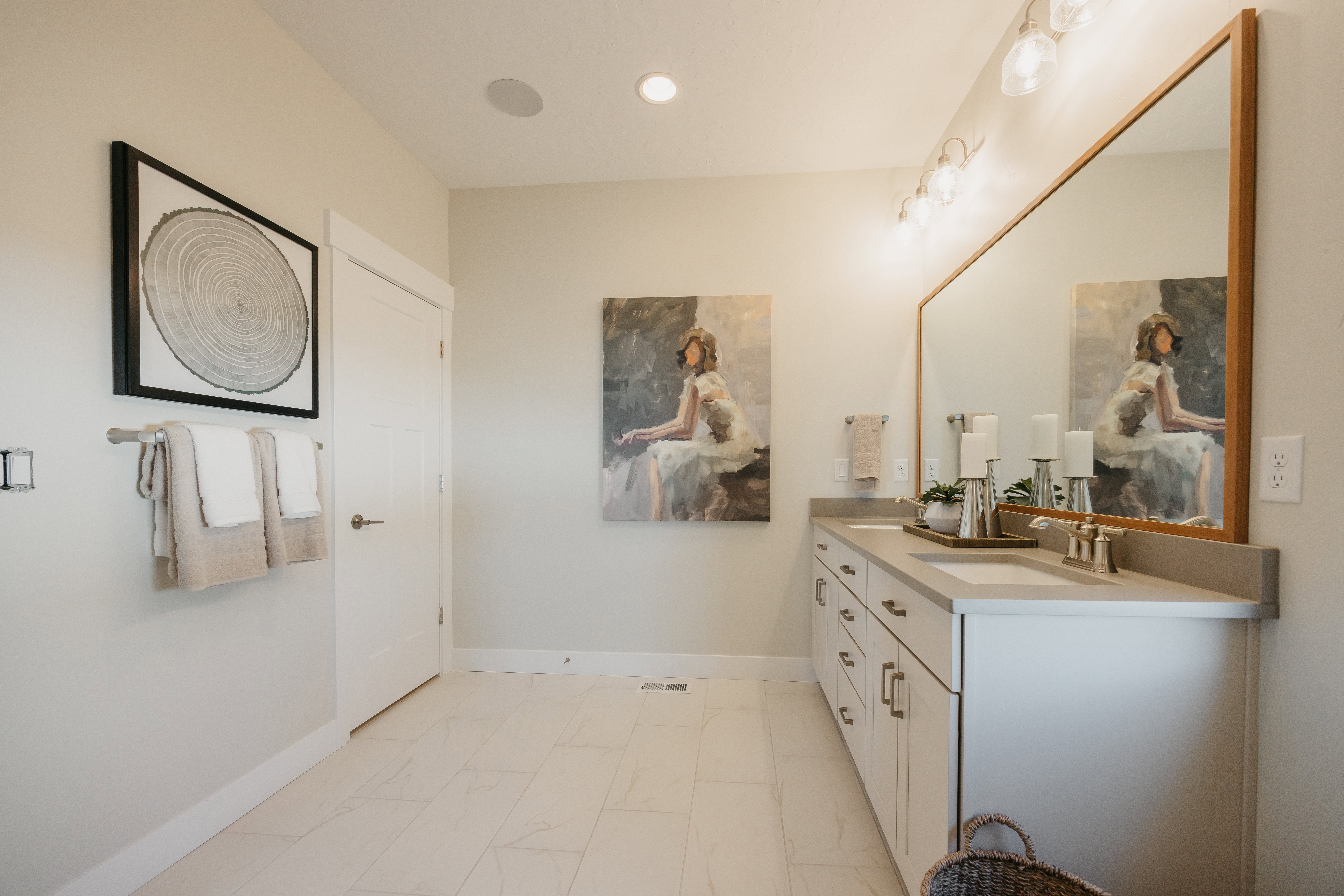 Double vanity with integrated sinks, light gray countertops, white cabinetry with brushed nickel pulls, and a large wood-framed mirror