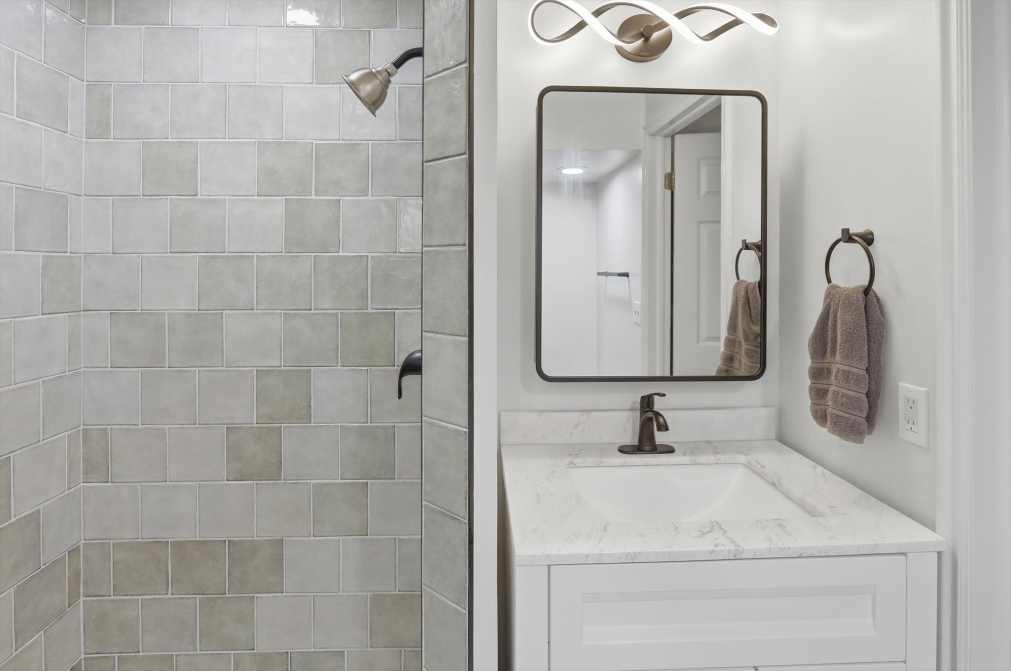 Bathroom vanity with a white rectangular sink, stone-finish countertop, and bronze-finish faucet
