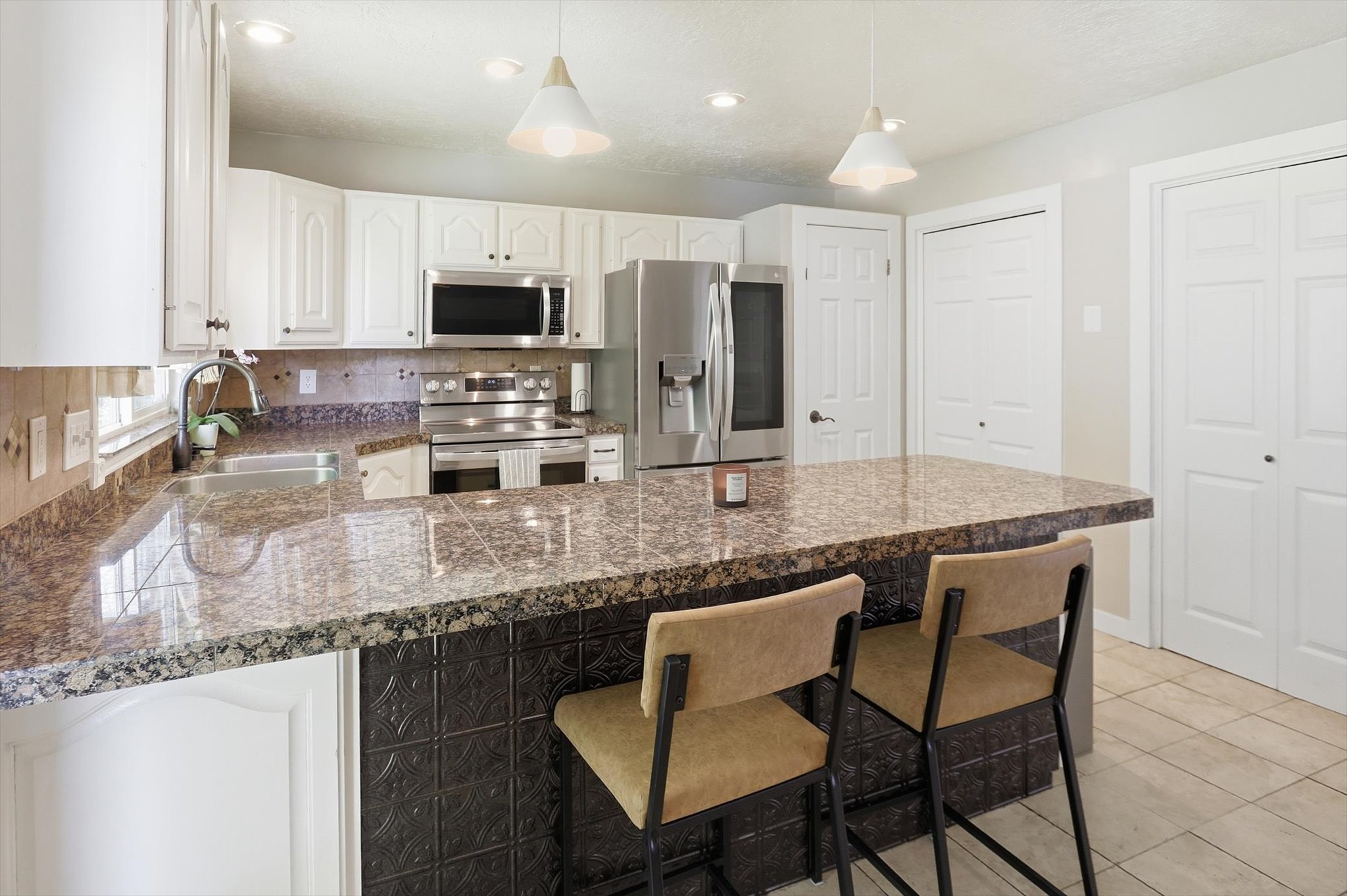 Kitchen featuring granite countertops, white cabinetry, stainless steel appliances, a tile backsplash, and recessed lighting