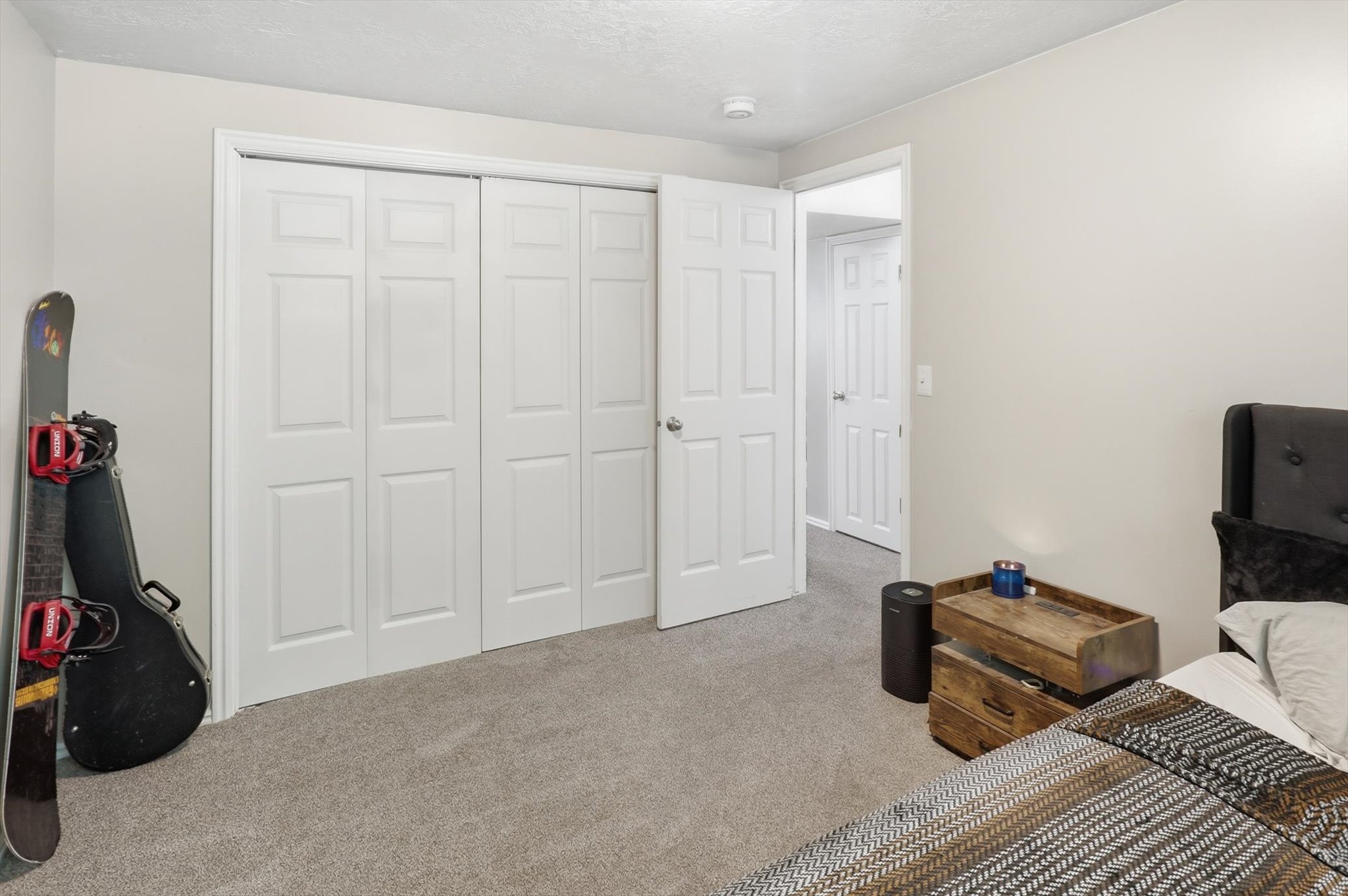 Bedroom featuring light gray wall paint, textured ceiling, a full bifold closet, and a white paneled door
