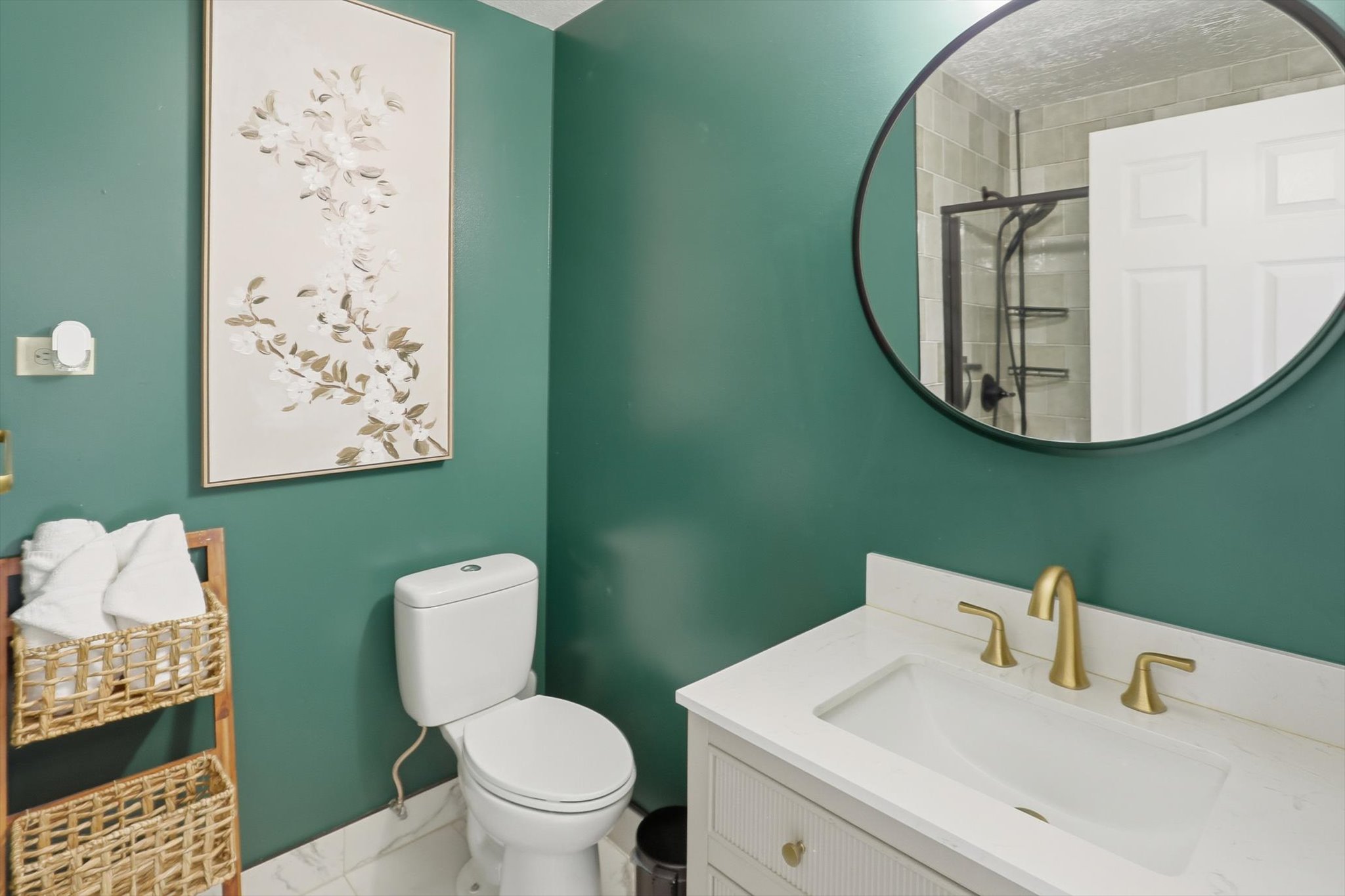 Bathroom featuring a white vanity with gold-tone hardware, a circular mirror, and a white toilet
