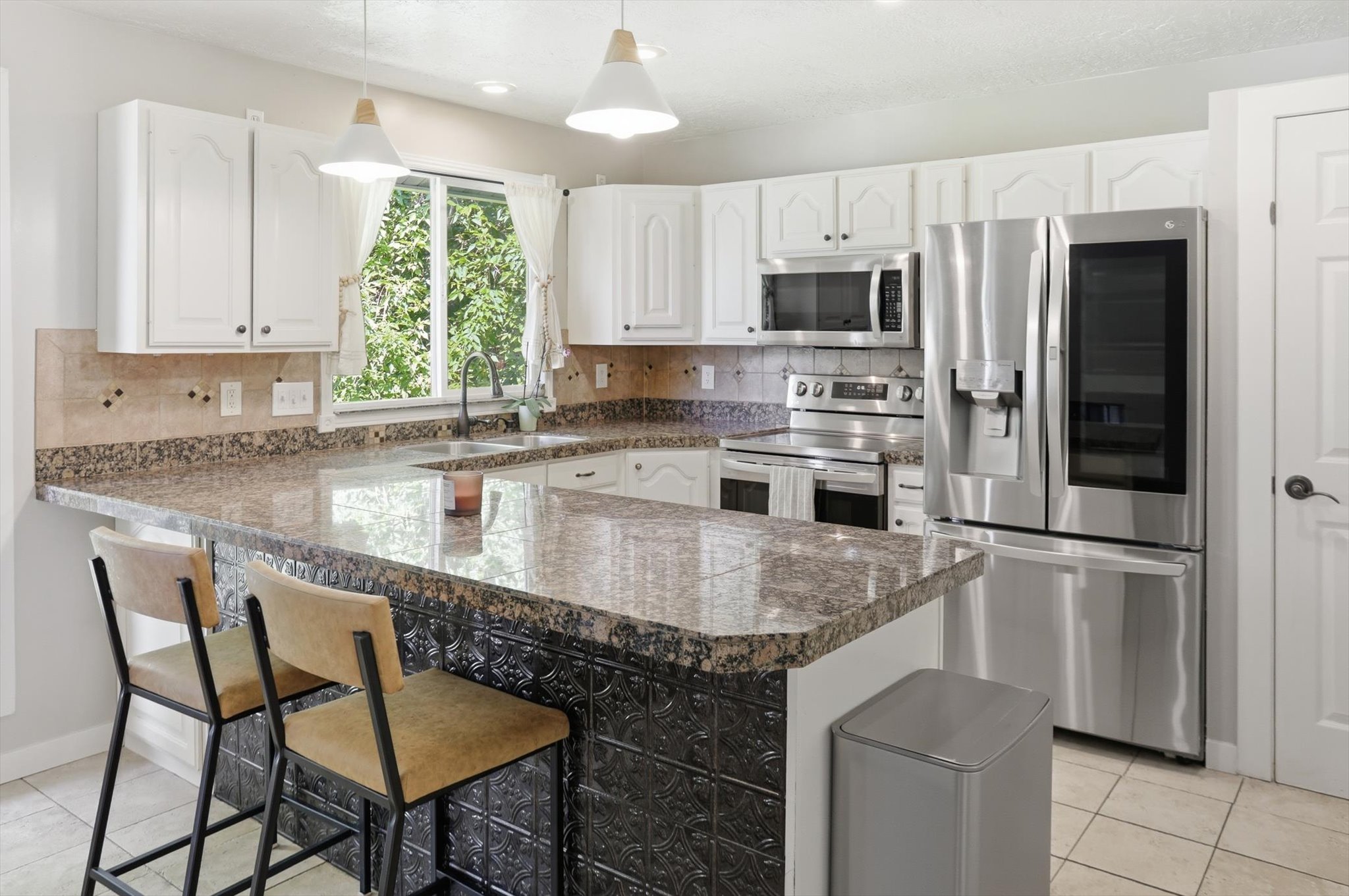 Kitchen featuring white cabinetry, stone-look countertops, stainless steel appliances, and a tiled backsplash