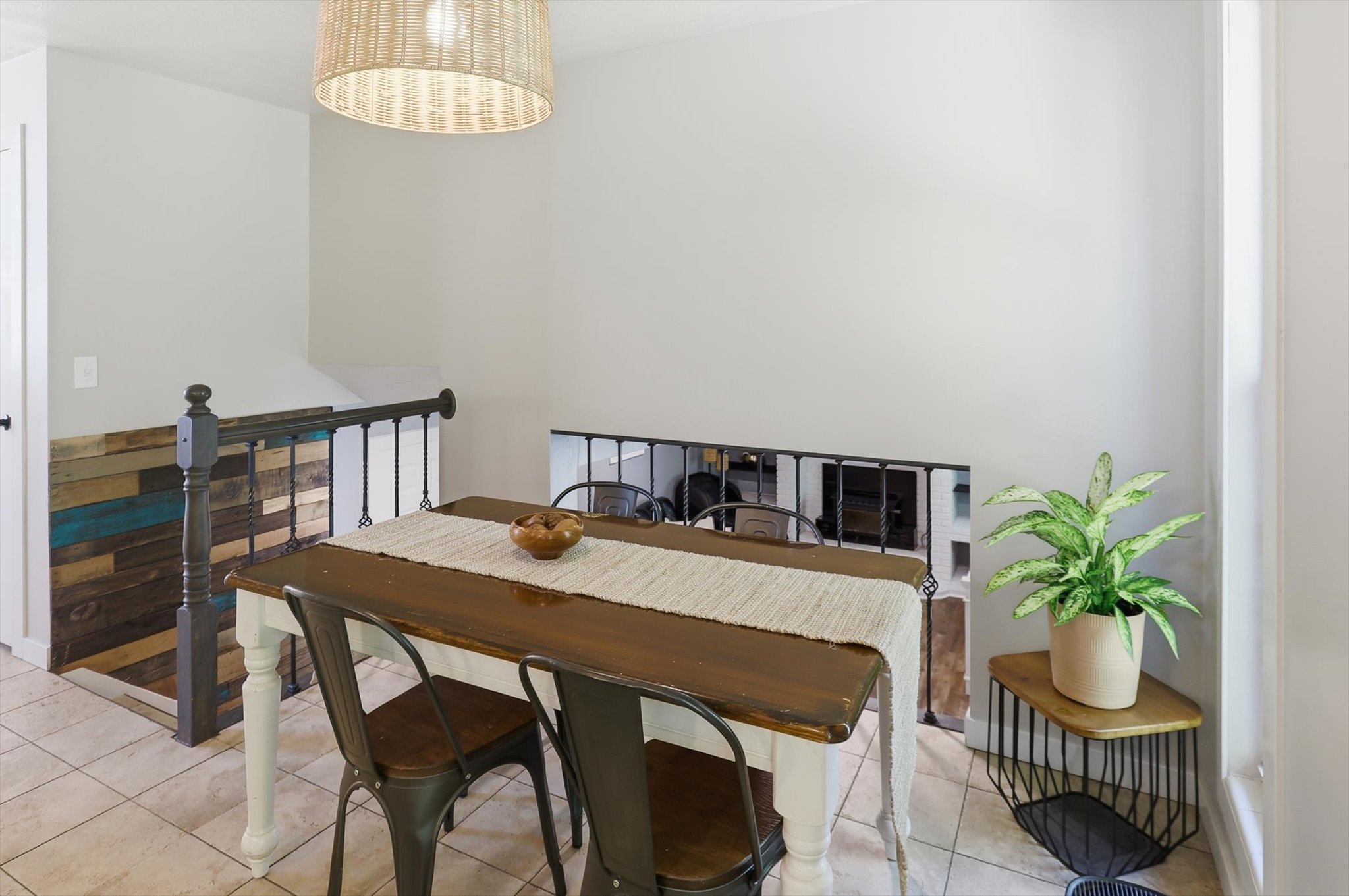 Dining area featuring a woven pendant light fixture, light tile flooring, and a decorative wood accent wall