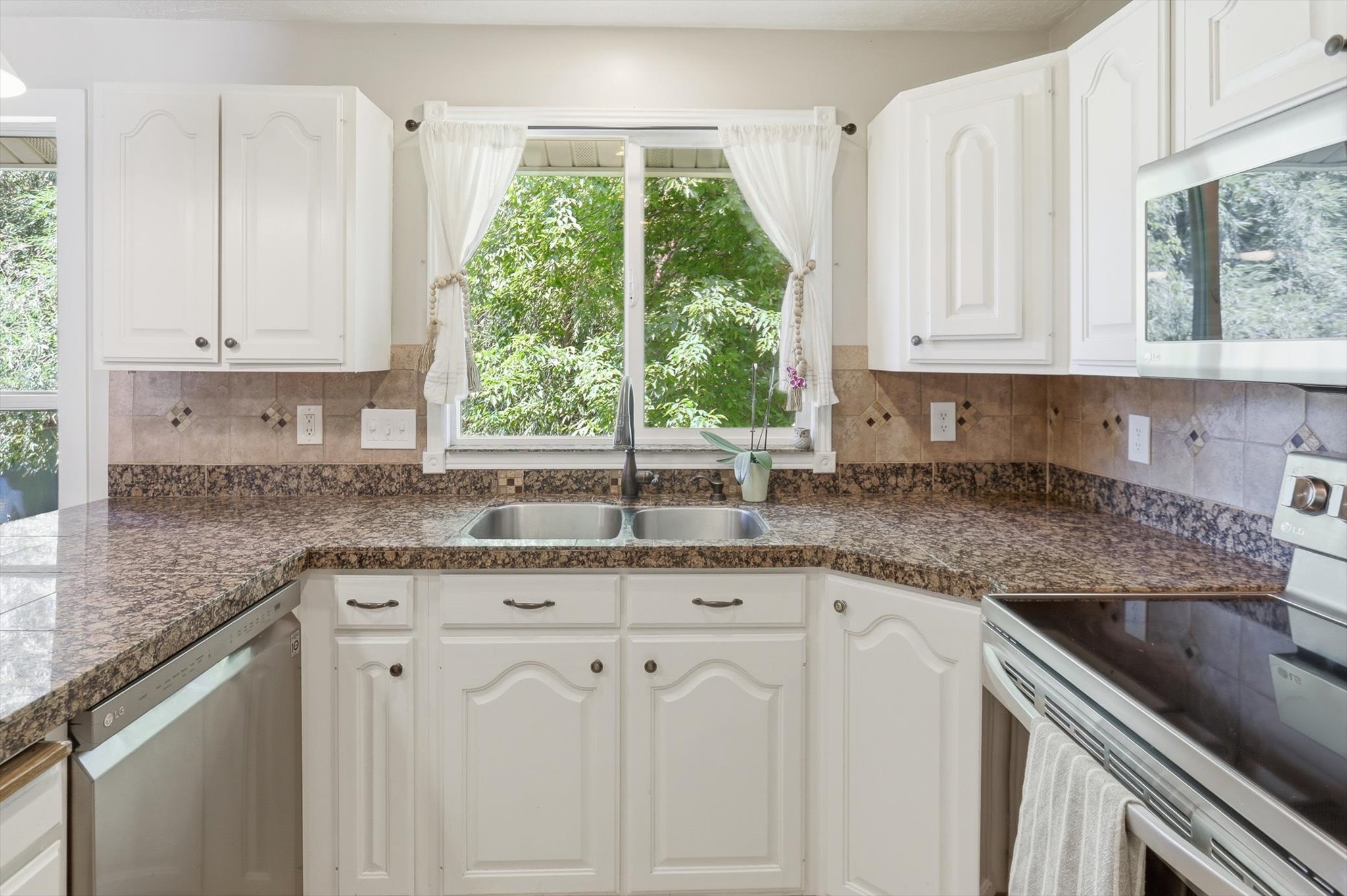 Kitchen featuring white cabinetry, brown granite-look countertops, and a tile backsplash
