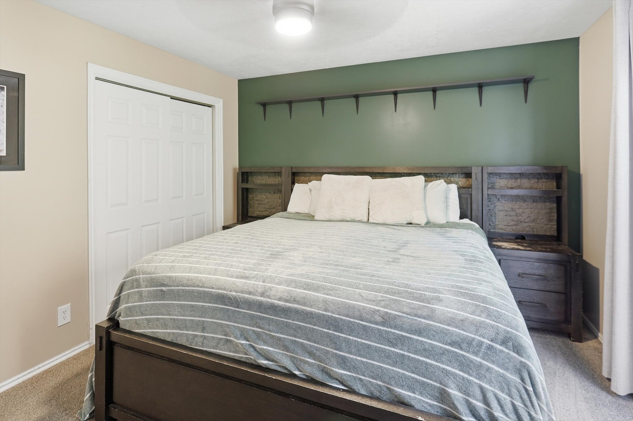Bedroom featuring a built-in wood-finish headboard with integrated side tables, a ceiling fan with integrated lighting, and neutral-toned wall paint
