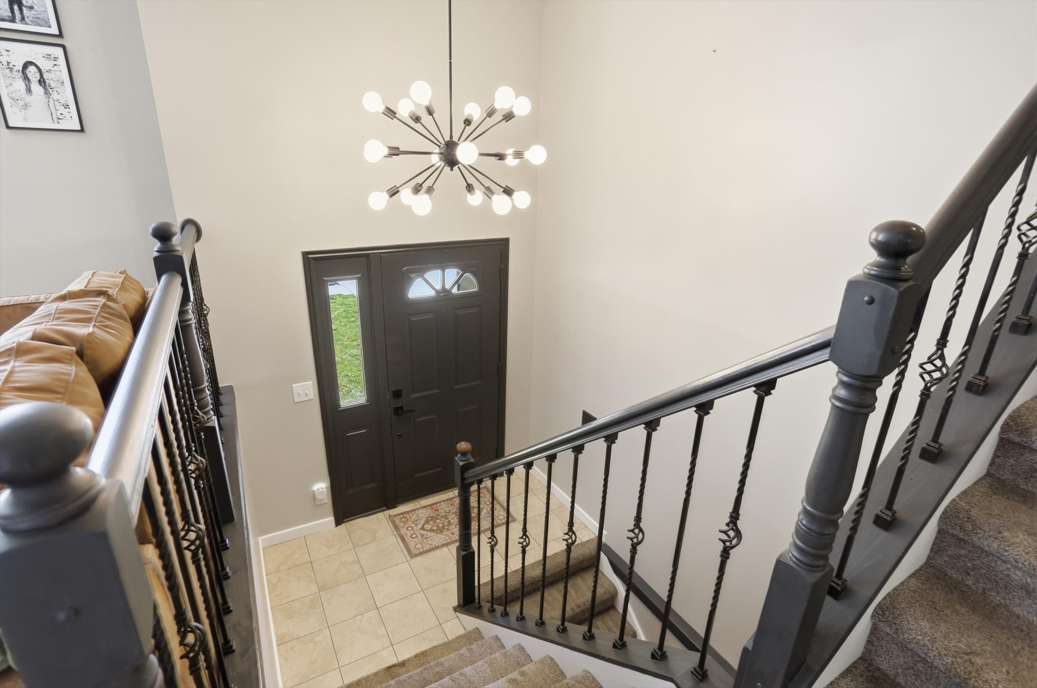 Foyer featuring a contemporary sputnik chandelier, dark paneled entry door with sidelight and transom window, and tiled flooring