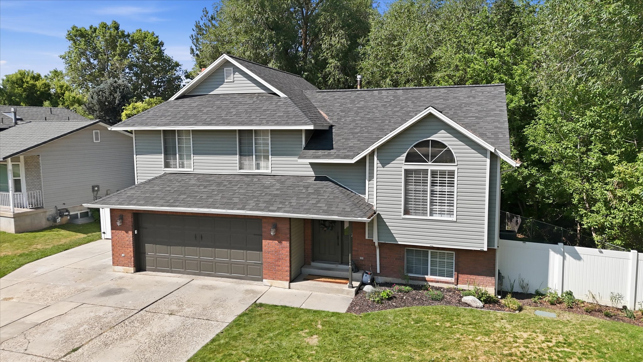 Two-story residence featuring light gray siding with brick accents and a multi-pitch shingle roof