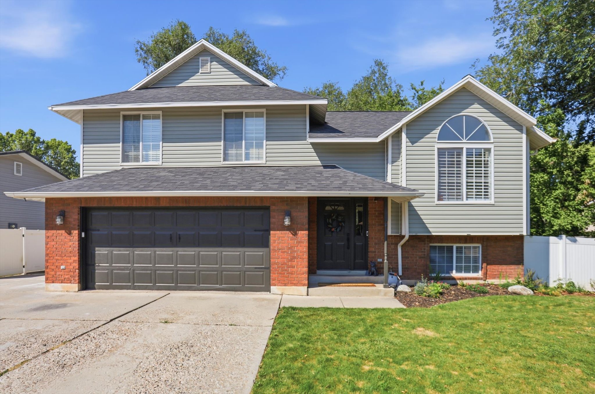 Two-story residence featuring a combination of light gray siding and red brick accents
