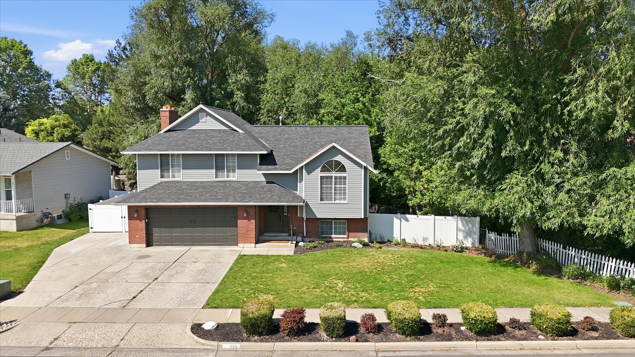 Two-story residence featuring gray siding, a two-car garage, and a brick facade
