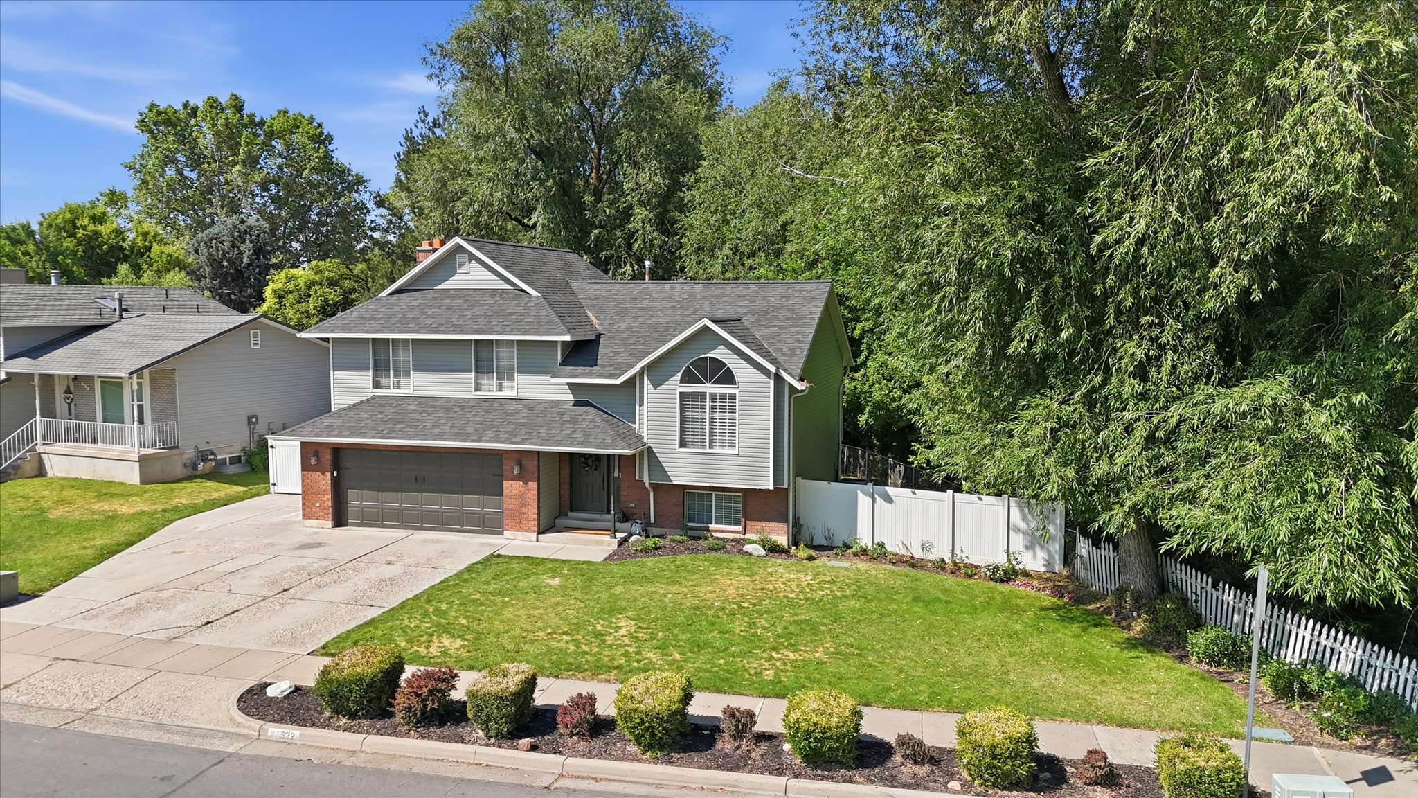 Two-story residence featuring light gray siding with brick accents and a dark shingle roof