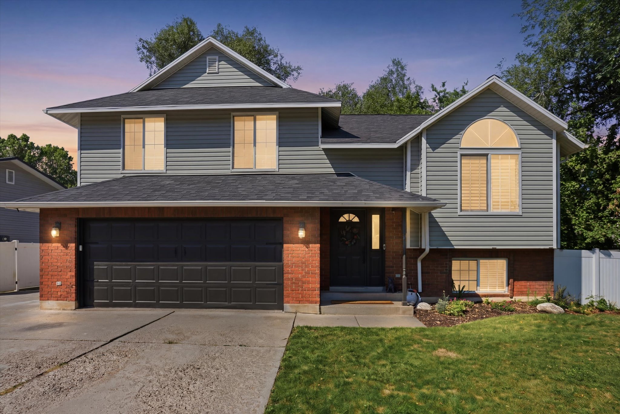 Two-story residence featuring a brick and siding exterior, an attached two-car garage, and a peaked roofline