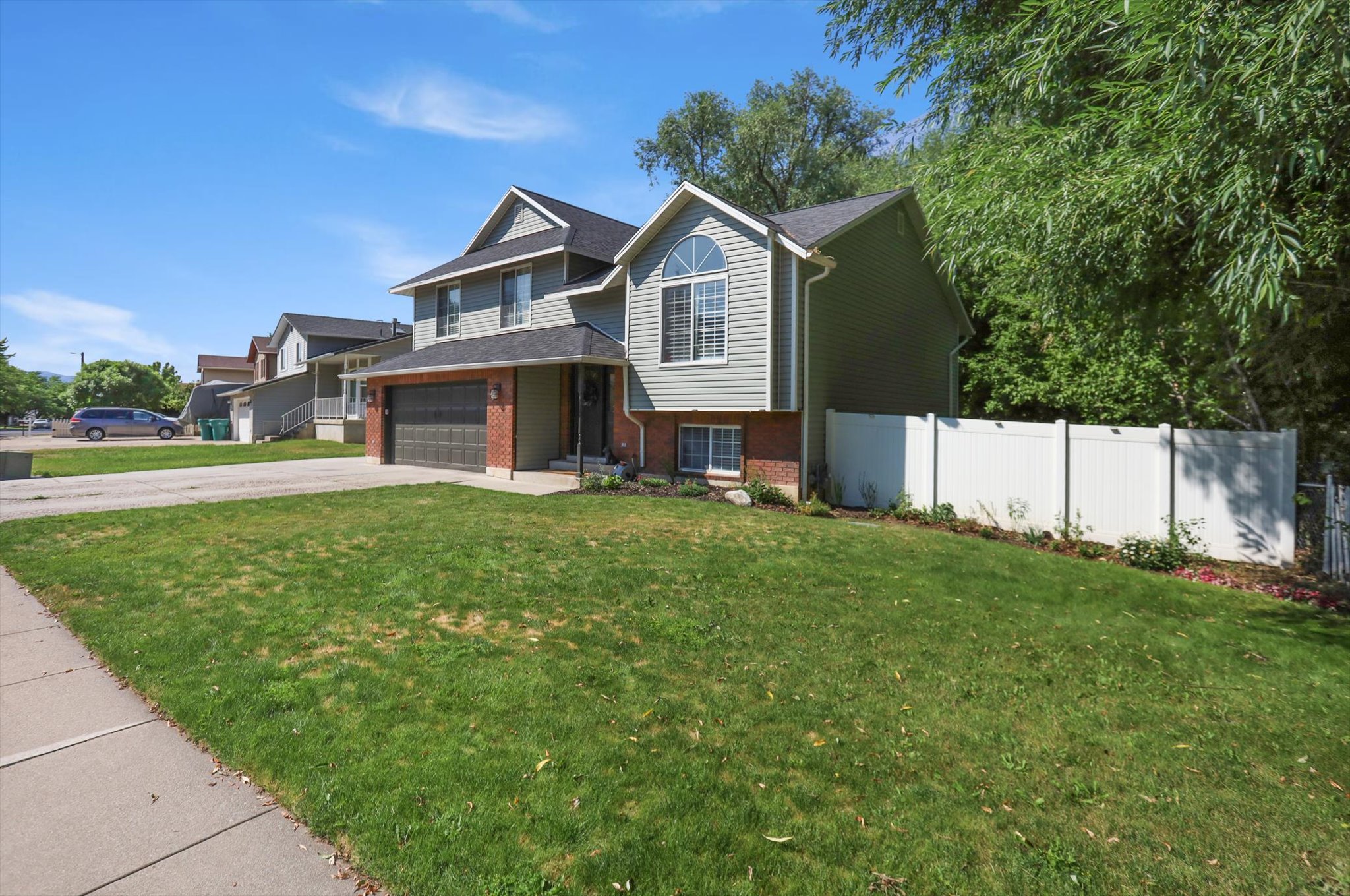 Two-story residence featuring light gray siding with brick accents and a dark shingle roof