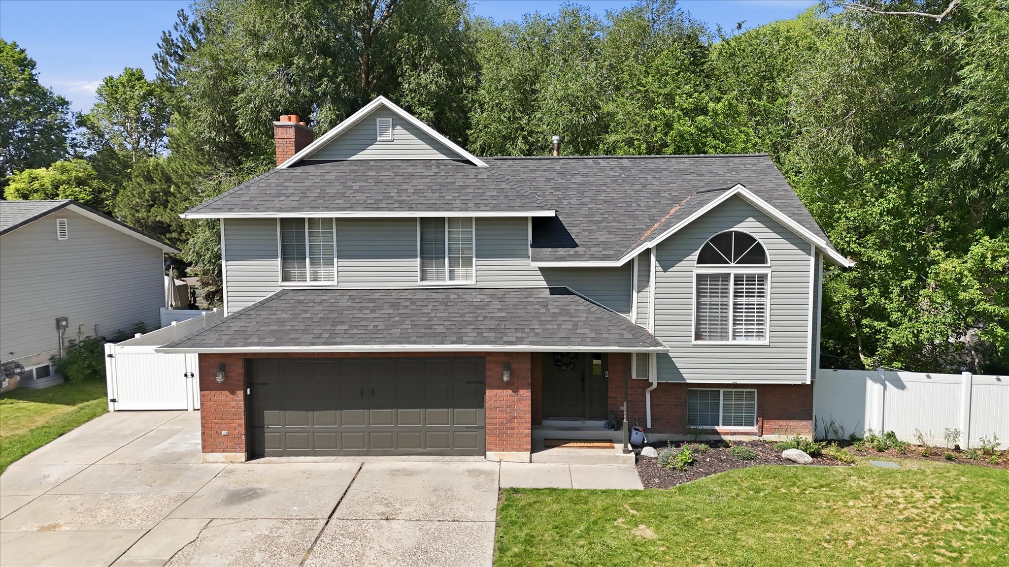 Contemporary two-story residence featuring a brick and siding exterior, an arched window, and a white privacy fence