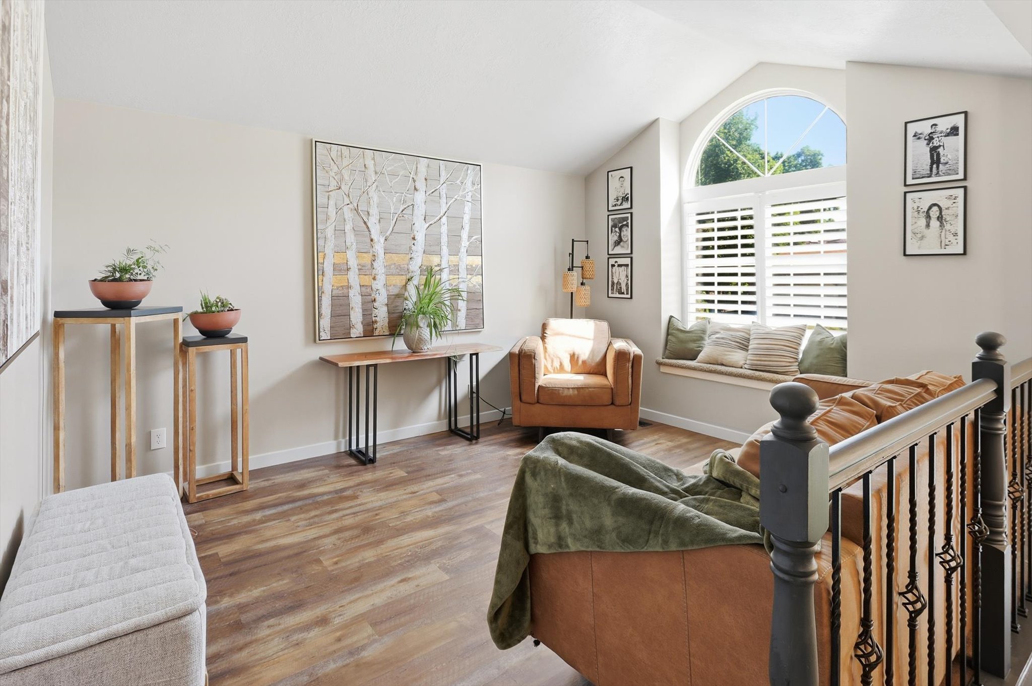 Vaulted ceiling living area featuring wood-finish flooring and a window seat with plantation shutters