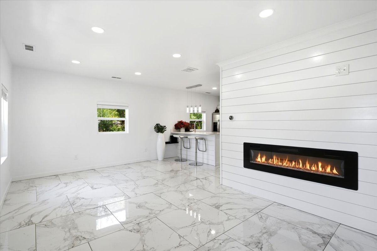 Spacious room featuring a linear fireplace set into a shiplap accent wall
