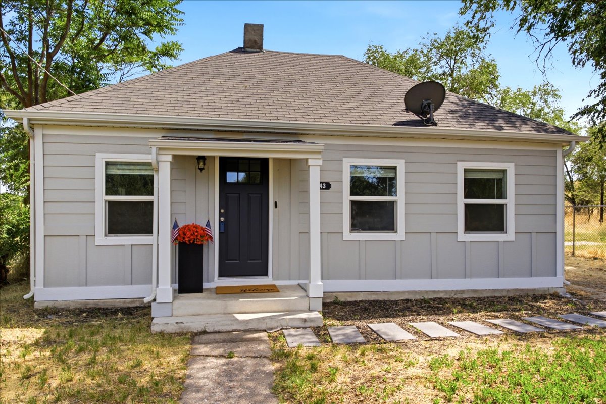 Light gray siding exterior with white trim and a dark gray entry door