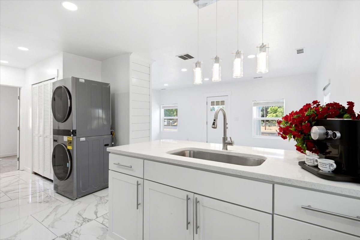 Kitchen island with an undermount sink, a gooseneck faucet, and light-toned countertops