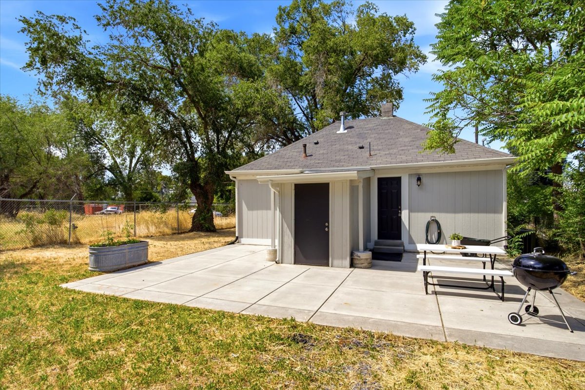 Expansive concrete patio with direct access to the auxiliary structure, featuring two entry doors and exterior lighting