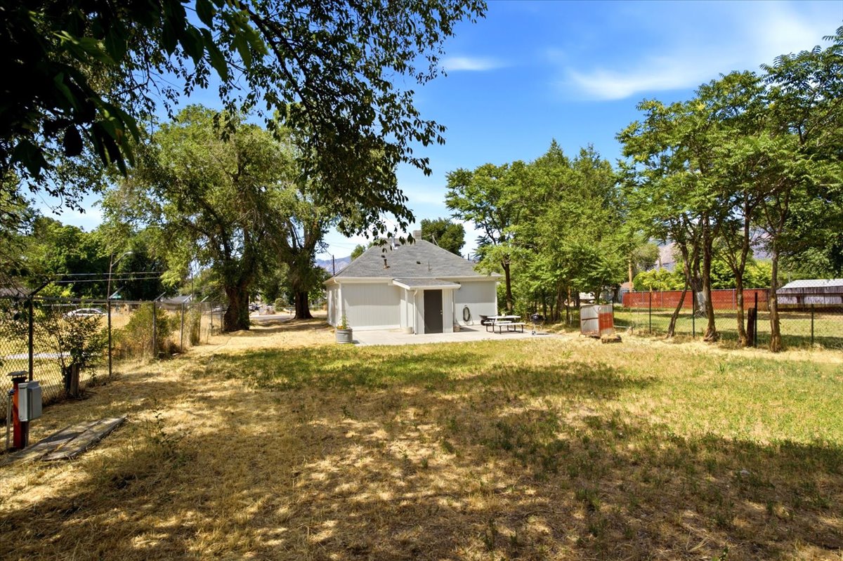 Expansive grassy yard with mature trees and perimeter fencing