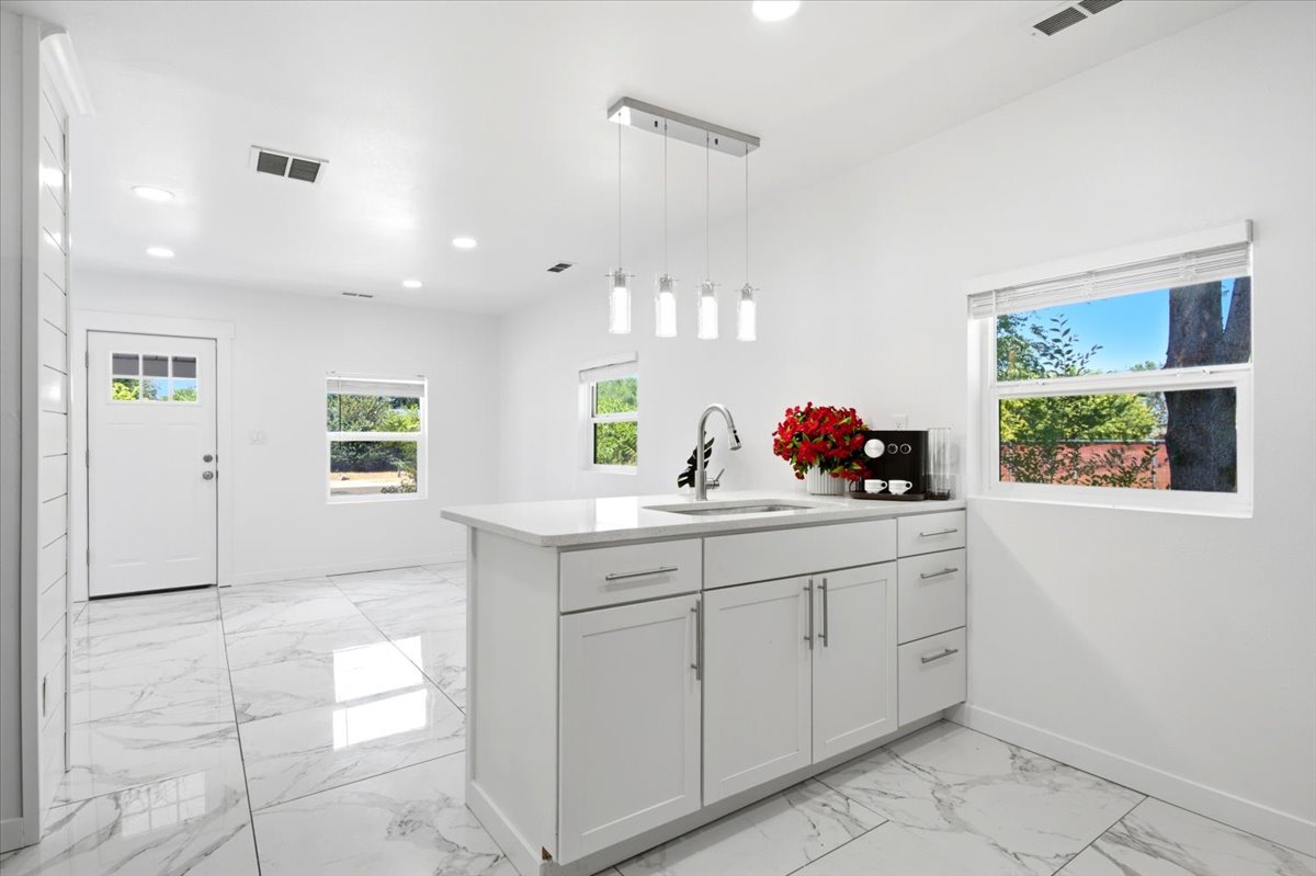 Open-concept interior featuring white-finish walls, marble-look tile flooring, and recessed lighting