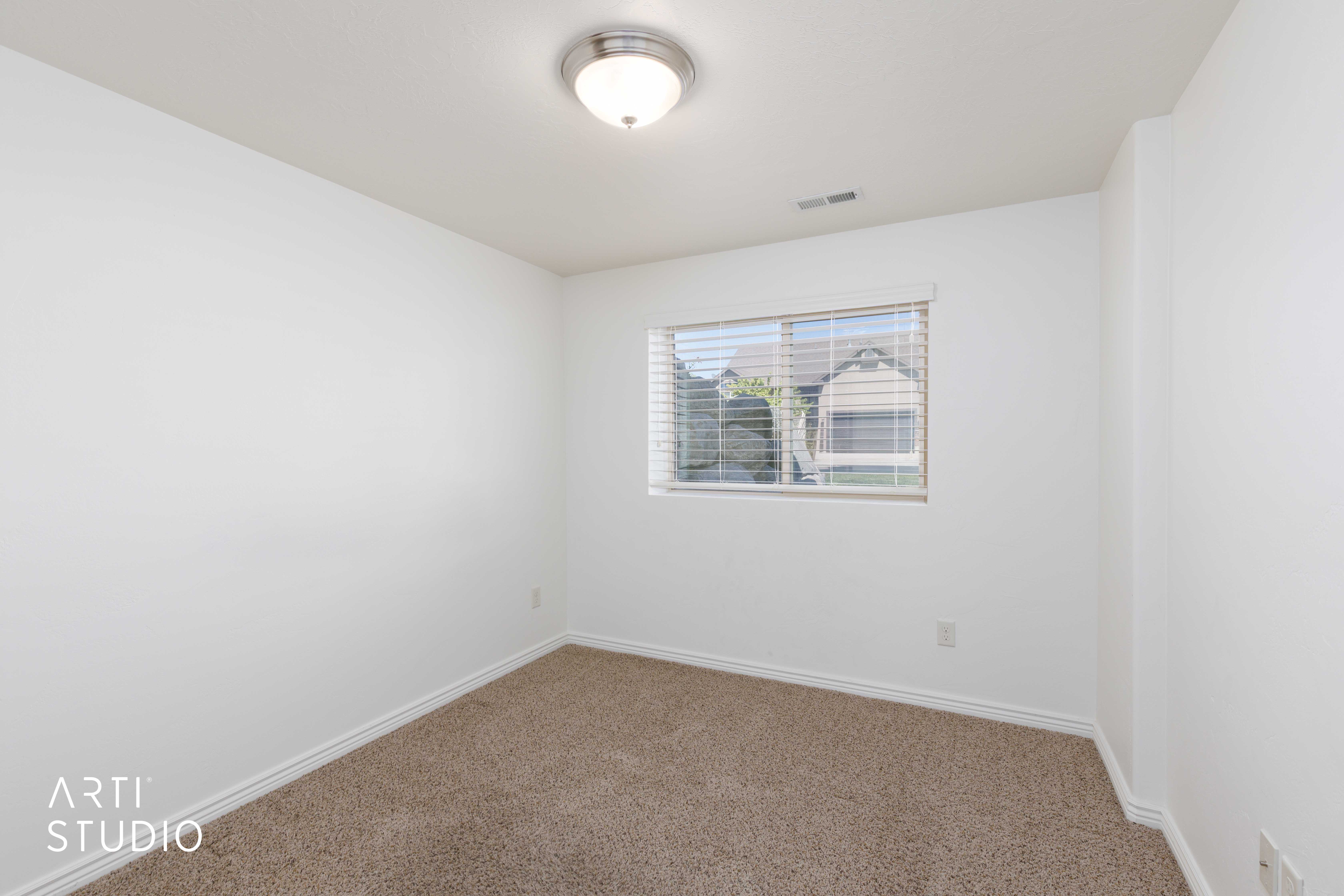 Carpeted room with white walls, a single window featuring blinds, and a flush-mount ceiling light fixture