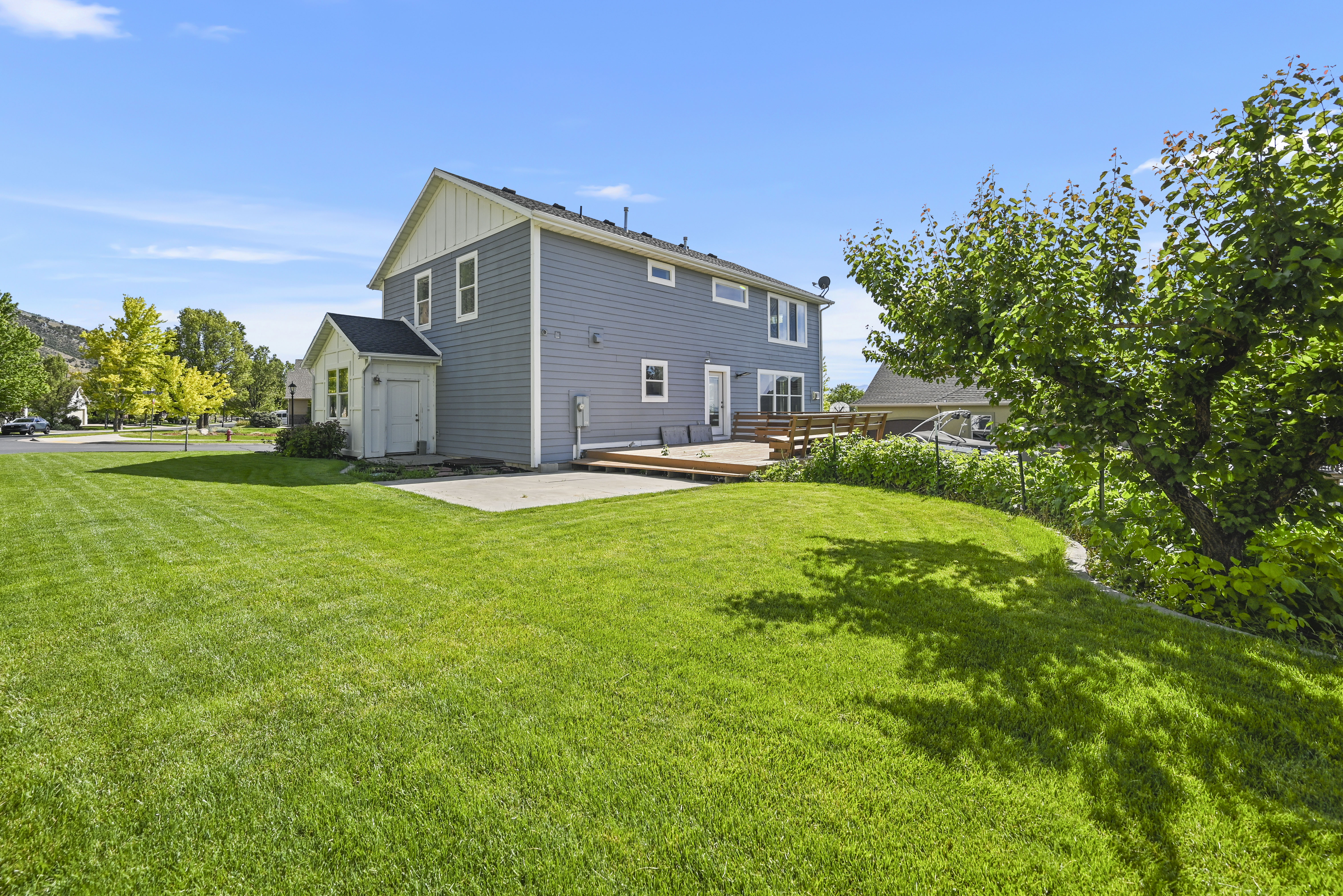 Expansive backyard featuring a lush lawn, a concrete patio, and a wood deck