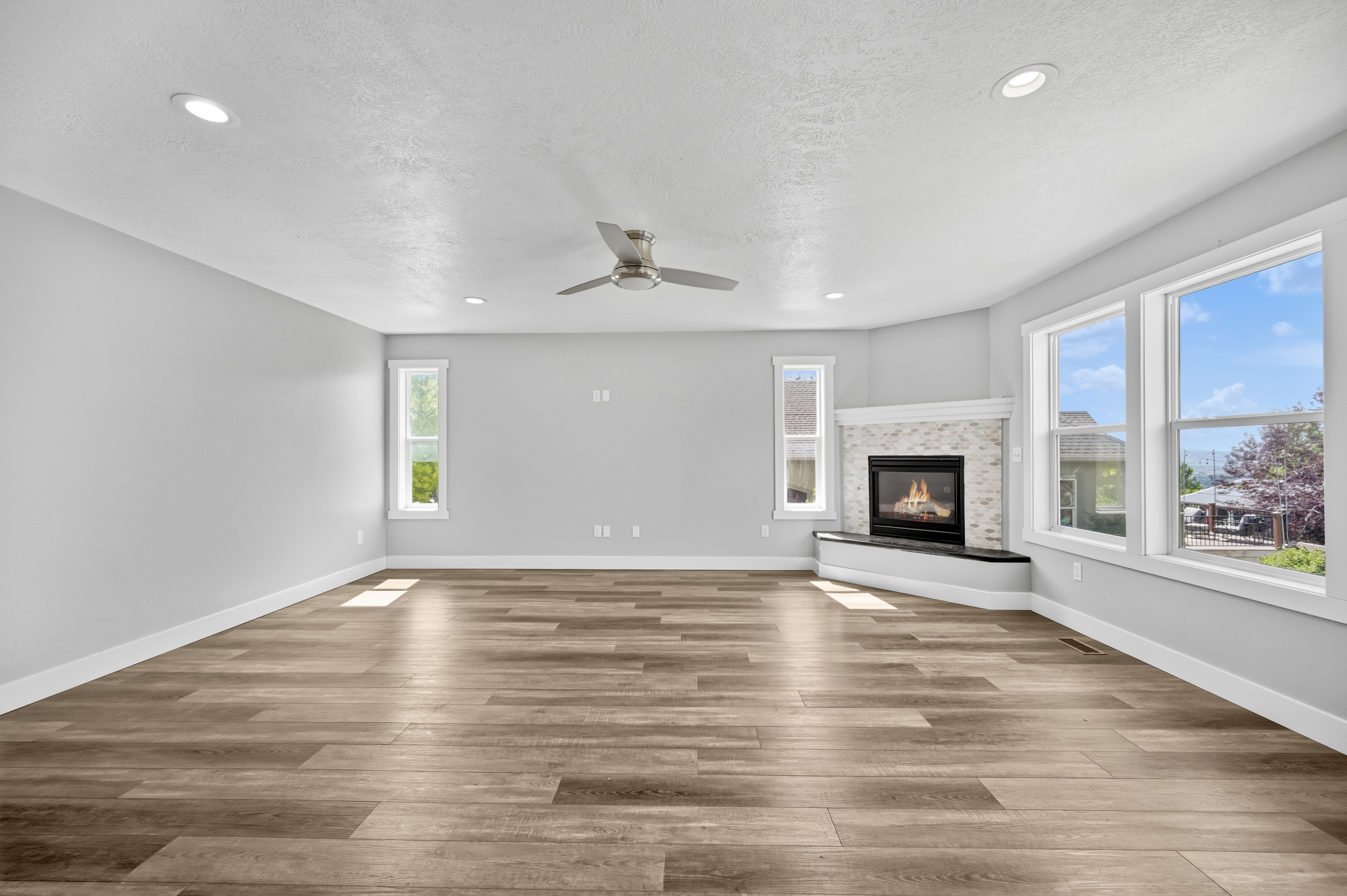 Spacious room featuring wood-finish flooring, recessed lighting, and a contemporary ceiling fan