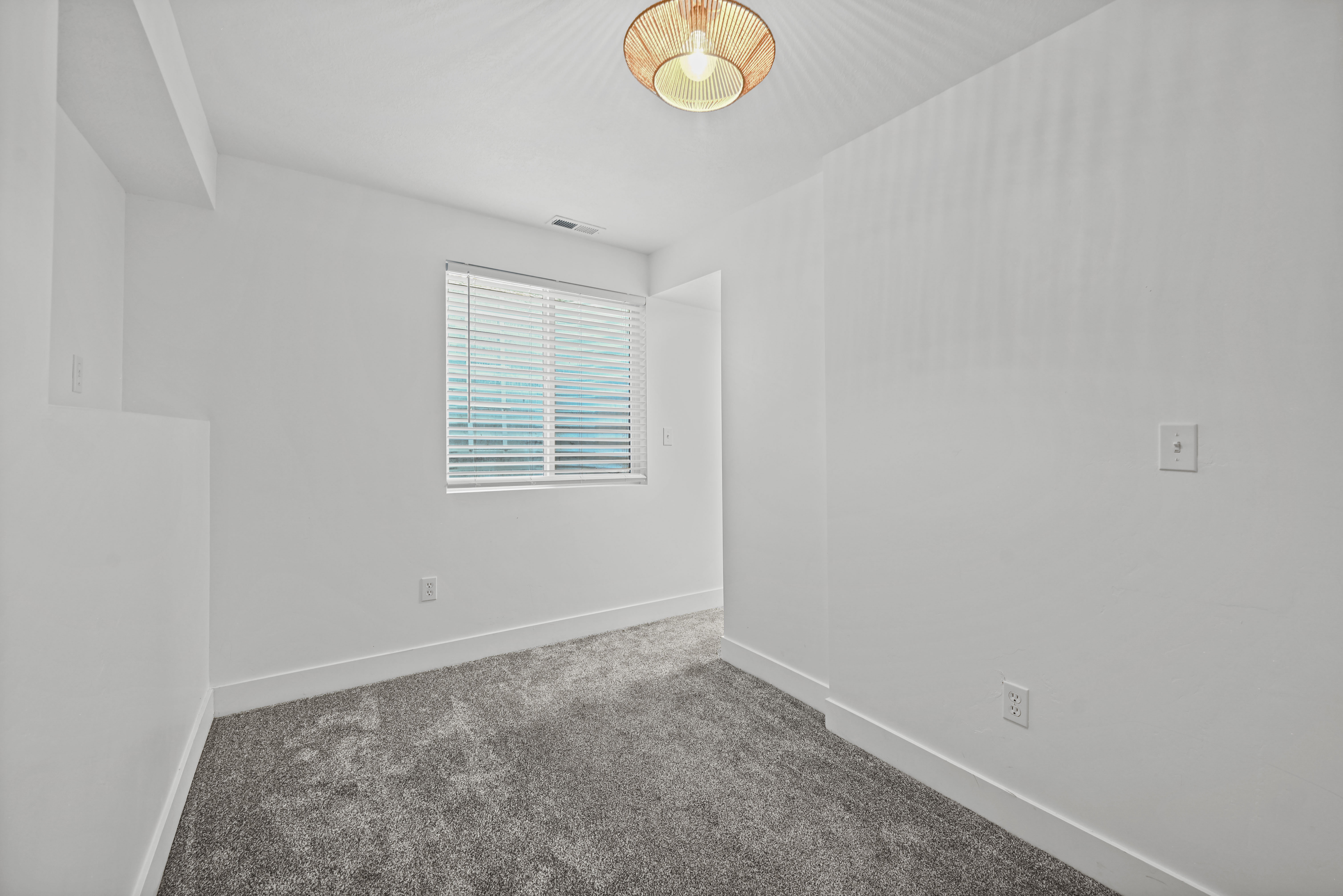 Neutral white walls complement the gray carpeting