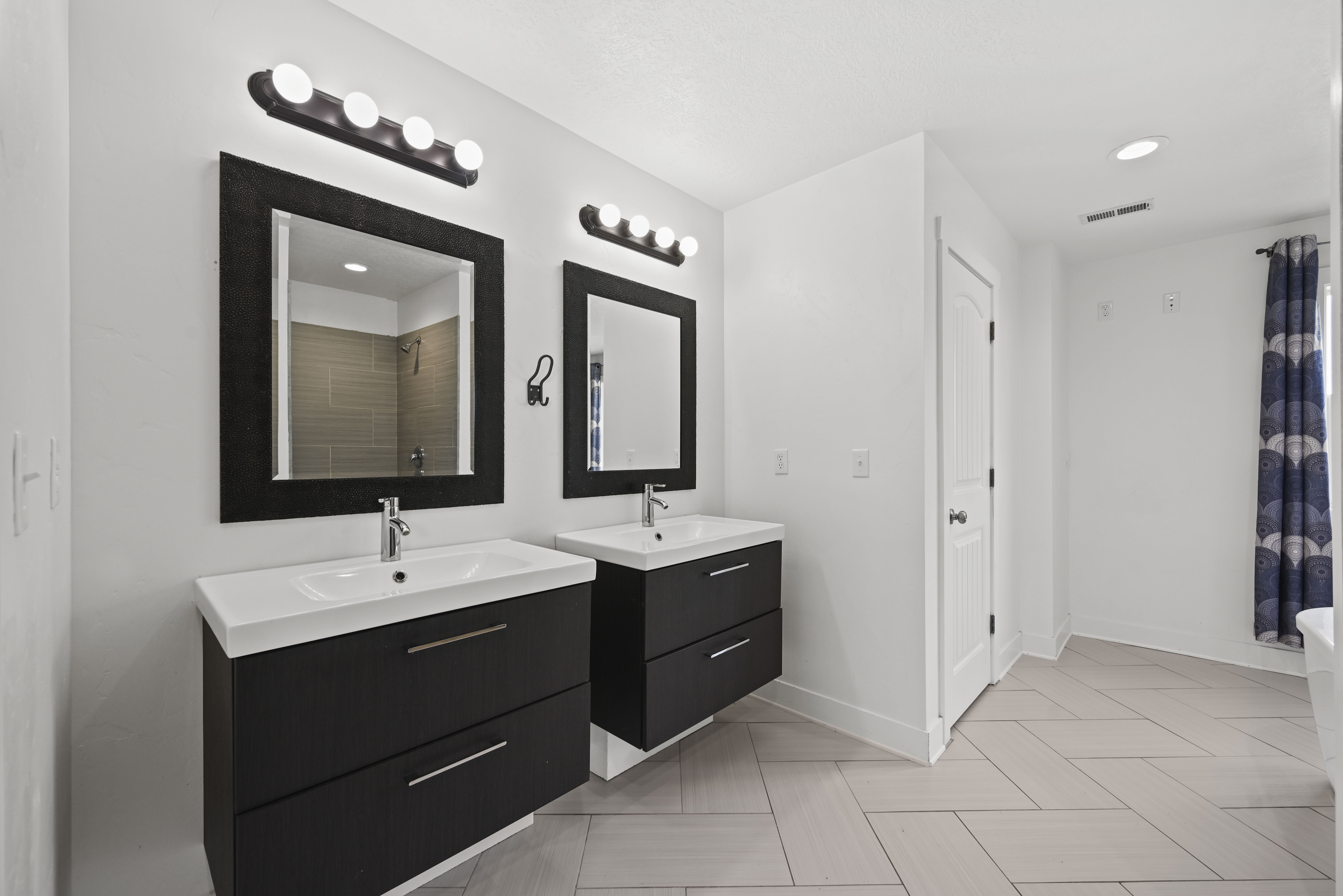 Dual floating vanities with integrated sinks, contemporary wall-mounted light fixtures, and coordinating framed mirrors