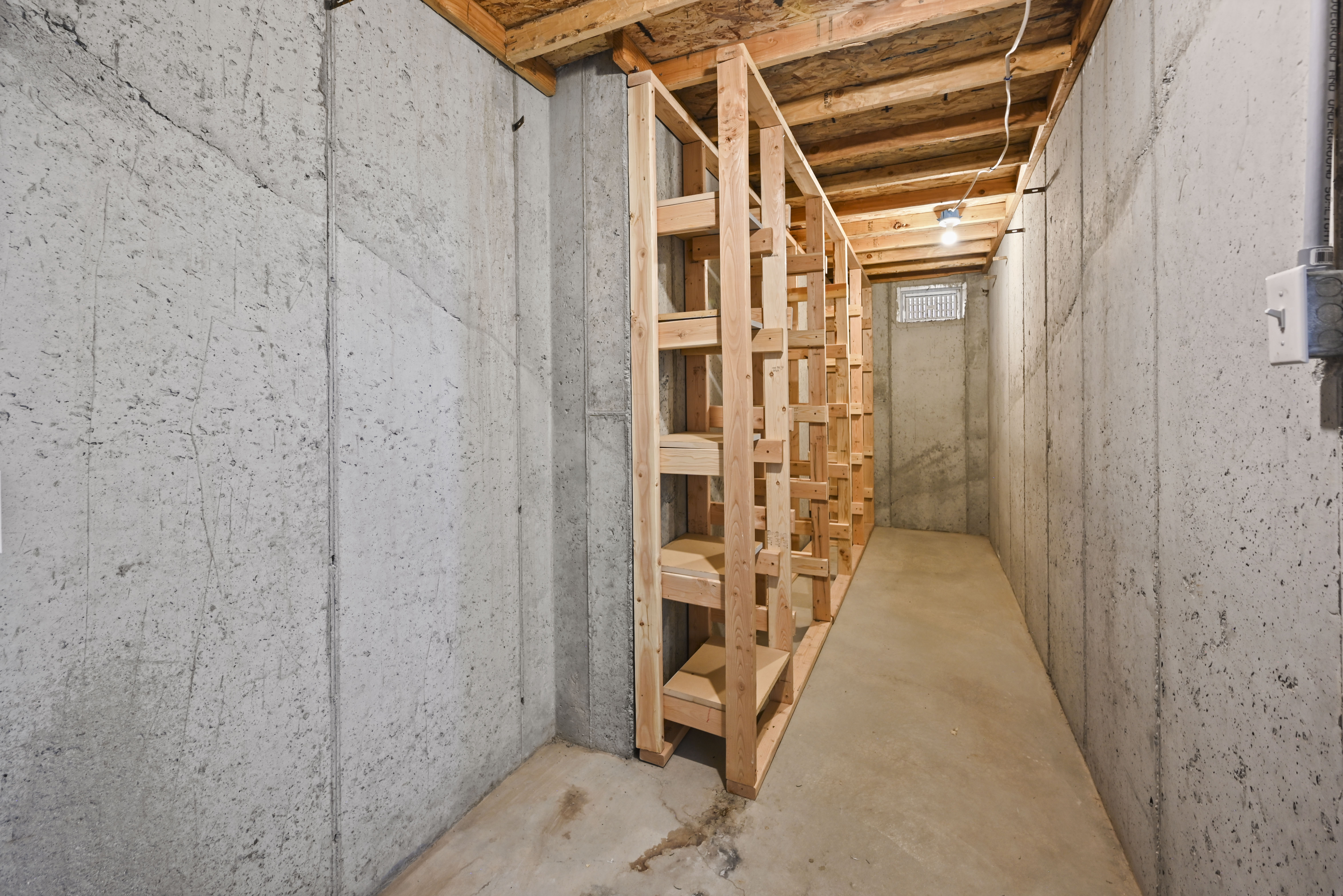Basement area featuring concrete walls, concrete flooring, and exposed wood ceiling joists