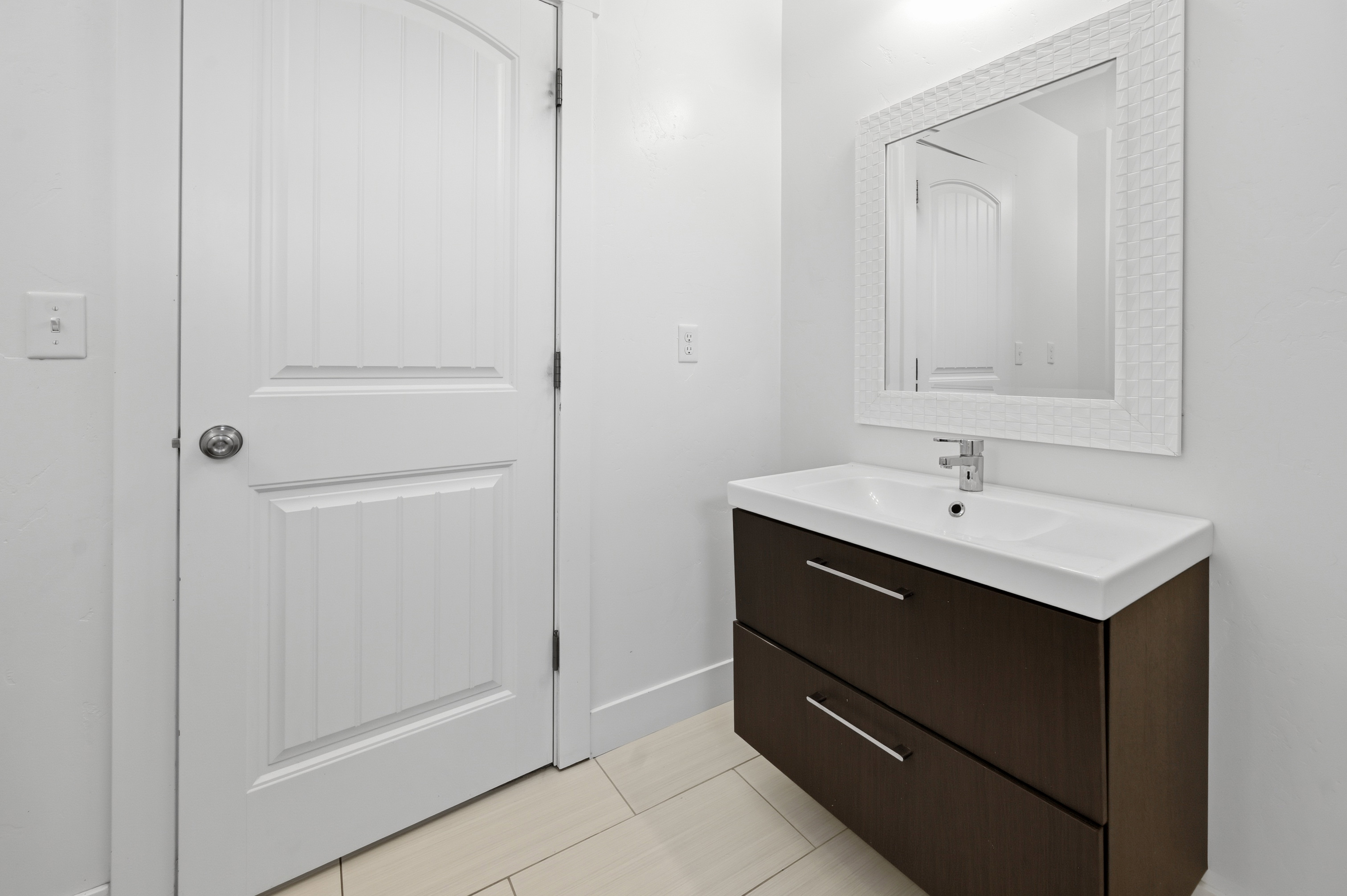 Floating vanity with integrated sink, chrome faucet, and dark wood-finish drawers