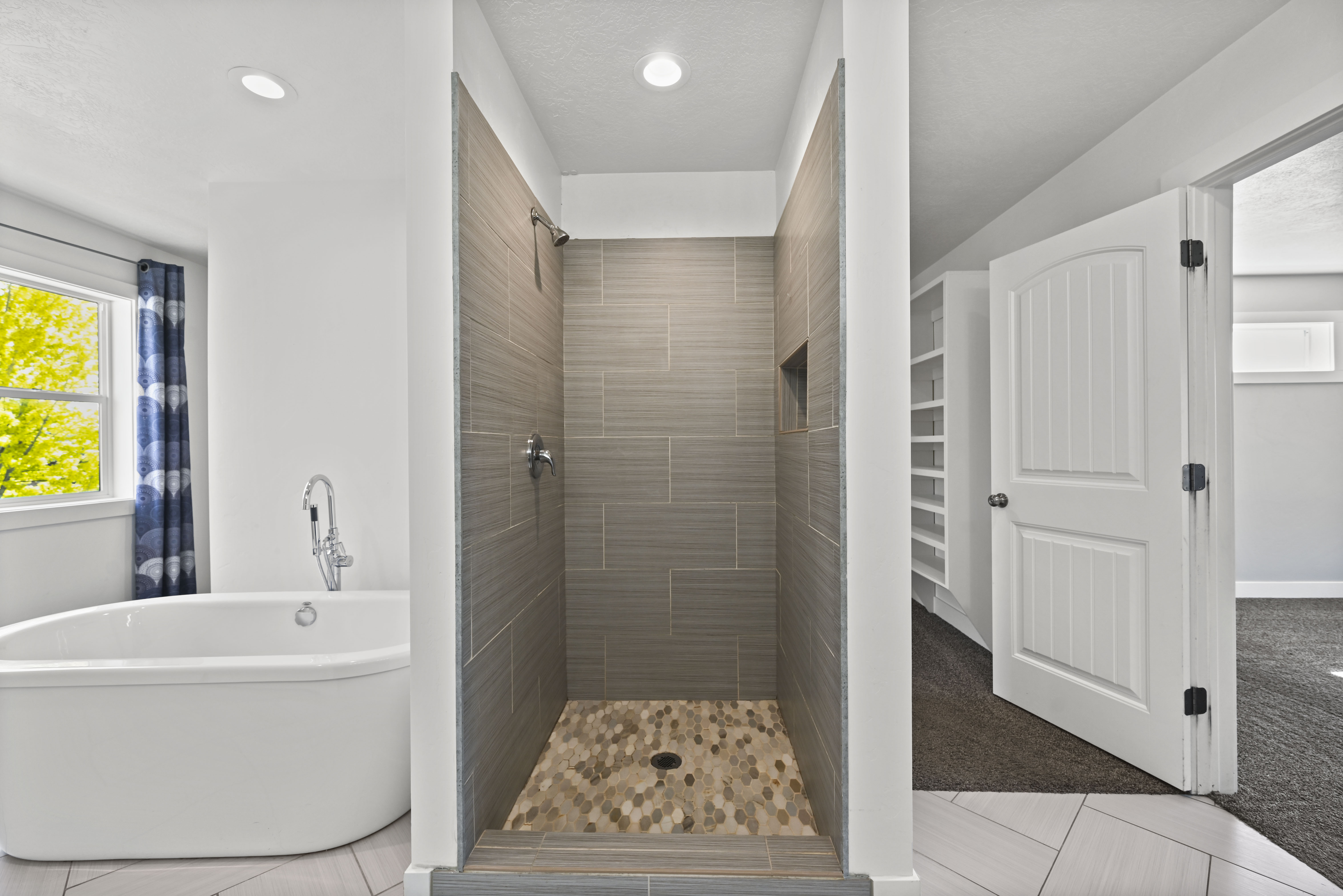 Contemporary bathroom featuring a freestanding soaking tub with a floor-mounted faucet, a walk-in shower with horizontal tile walls, a built-in shower niche, and a mosaic tile shower floor