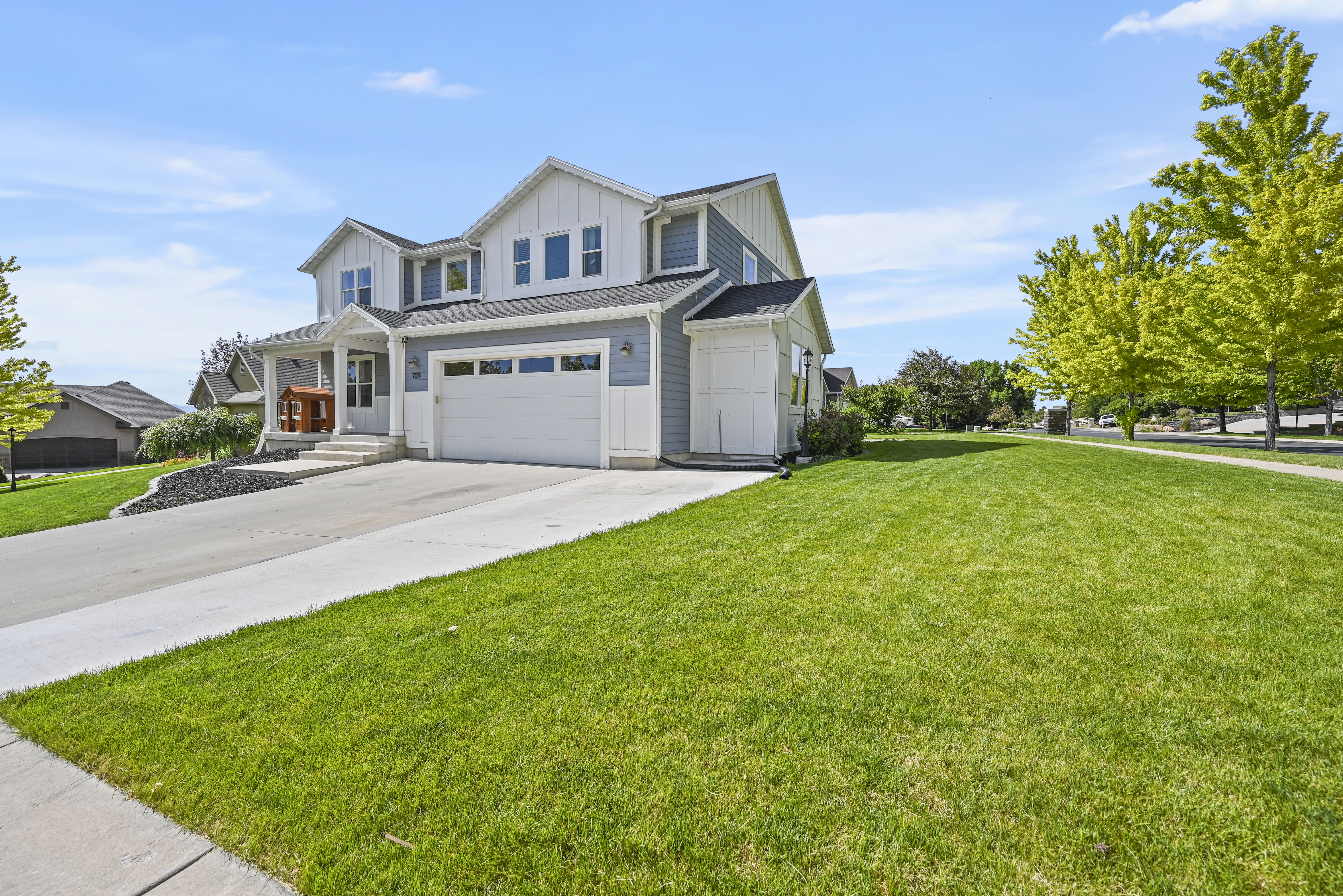Contemporary two-story residence featuring light gray siding and white vertical accents