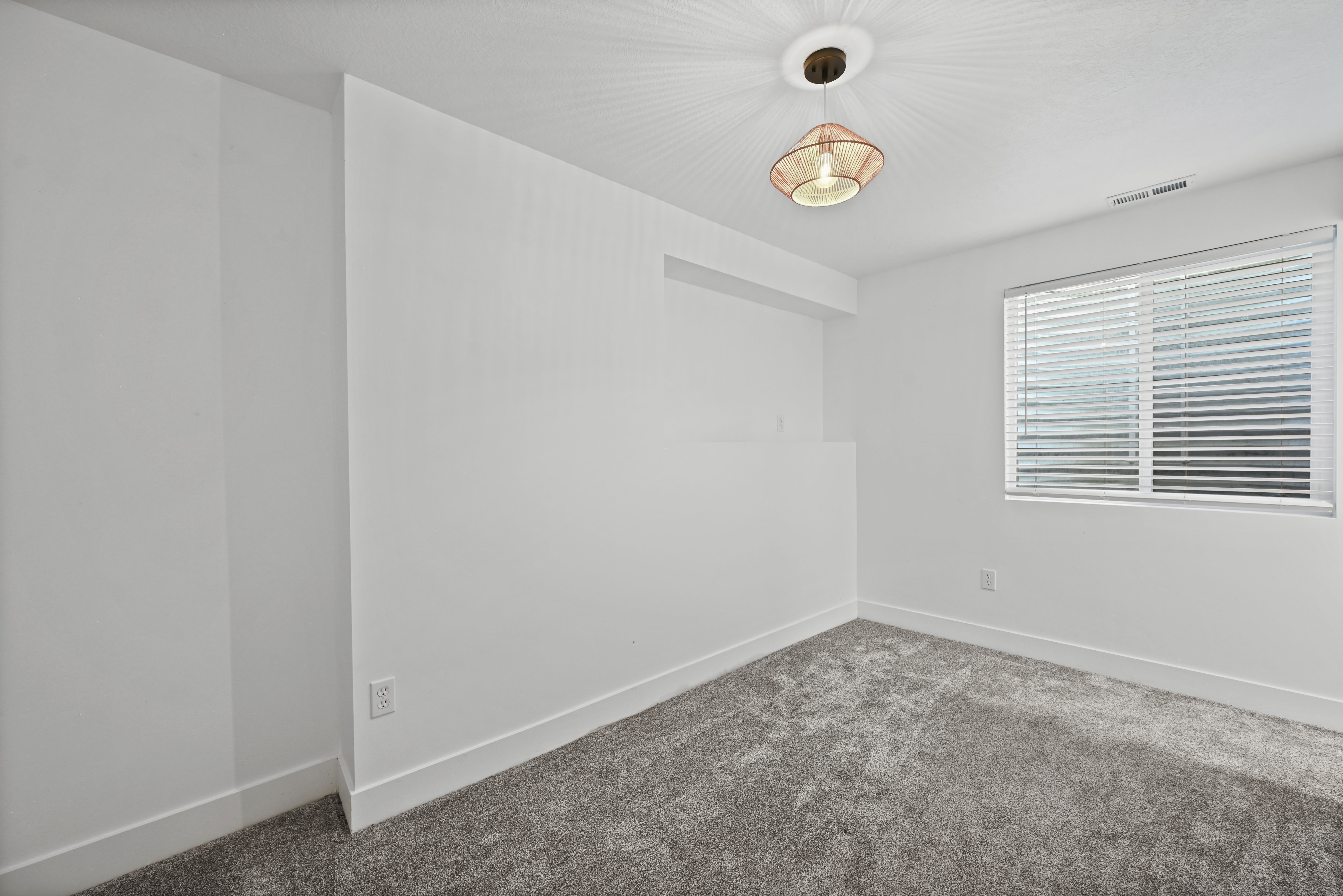 Carpeted room featuring a single window with horizontal blinds, a ceiling-mounted light fixture, and white baseboards