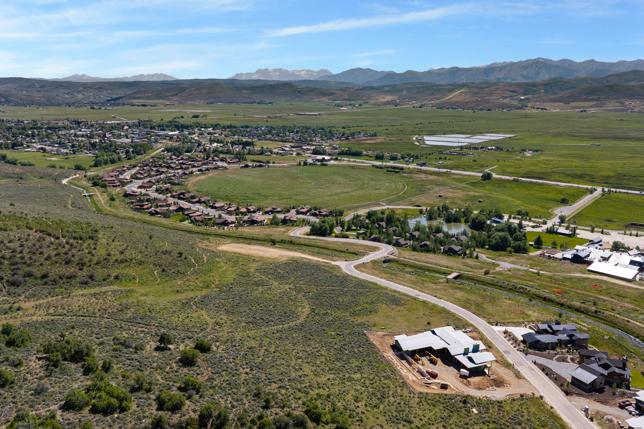 Expansive aerial perspective showcasing a residential development nestled within a verdant valley, framed by distant mountains
