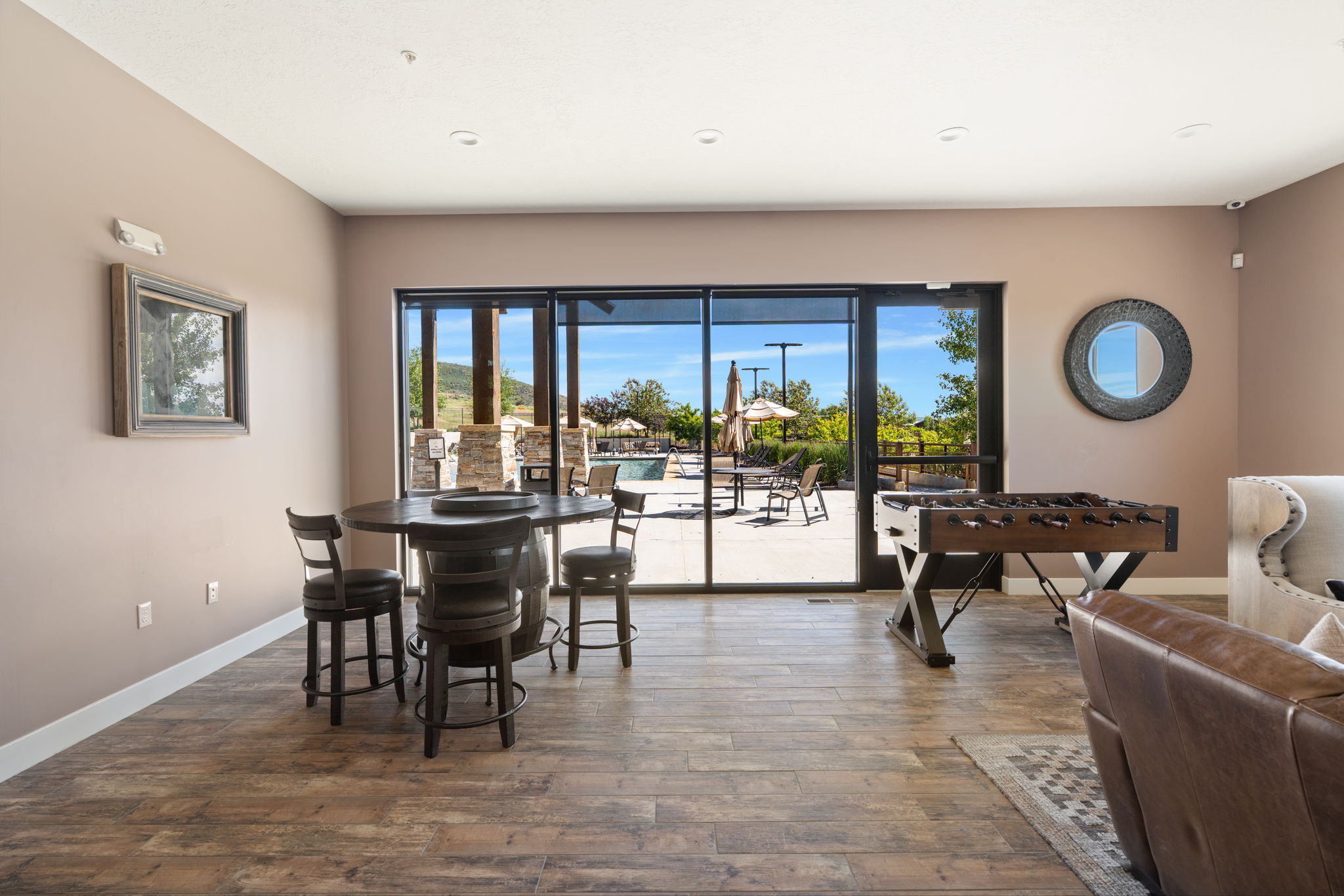 Entertainment space featuring wood-finish flooring, recessed lighting, and expansive glass sliding doors opening to an exterior patio