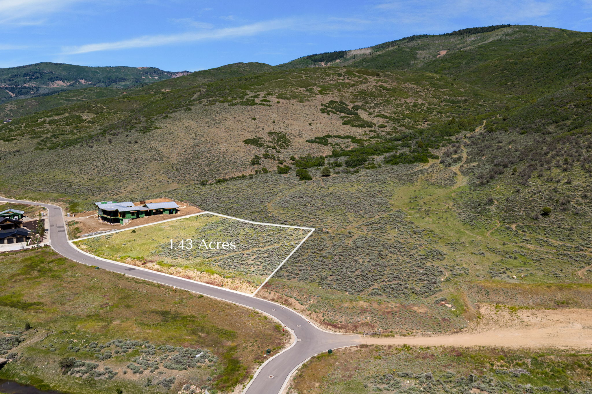 Cleared 1.43-acre lot featuring a paved road frontage, defined property lines, and a mountainous natural backdrop
