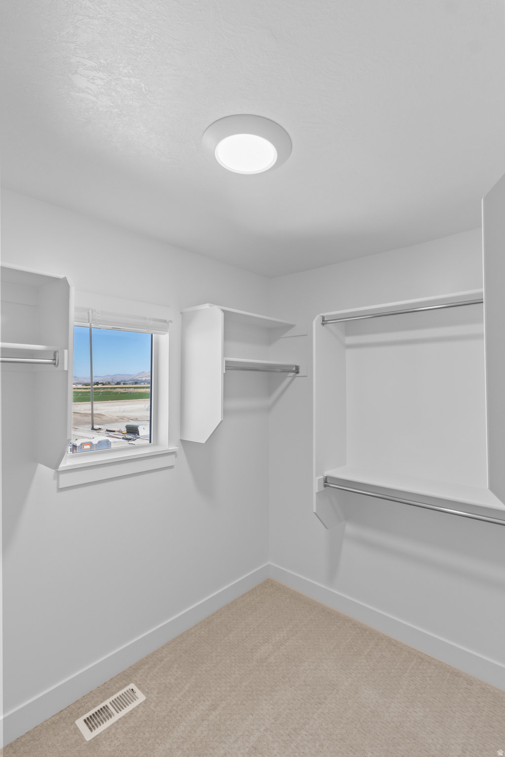 Walk-in closet featuring built-in shelving, hanging rods, and a window for natural light